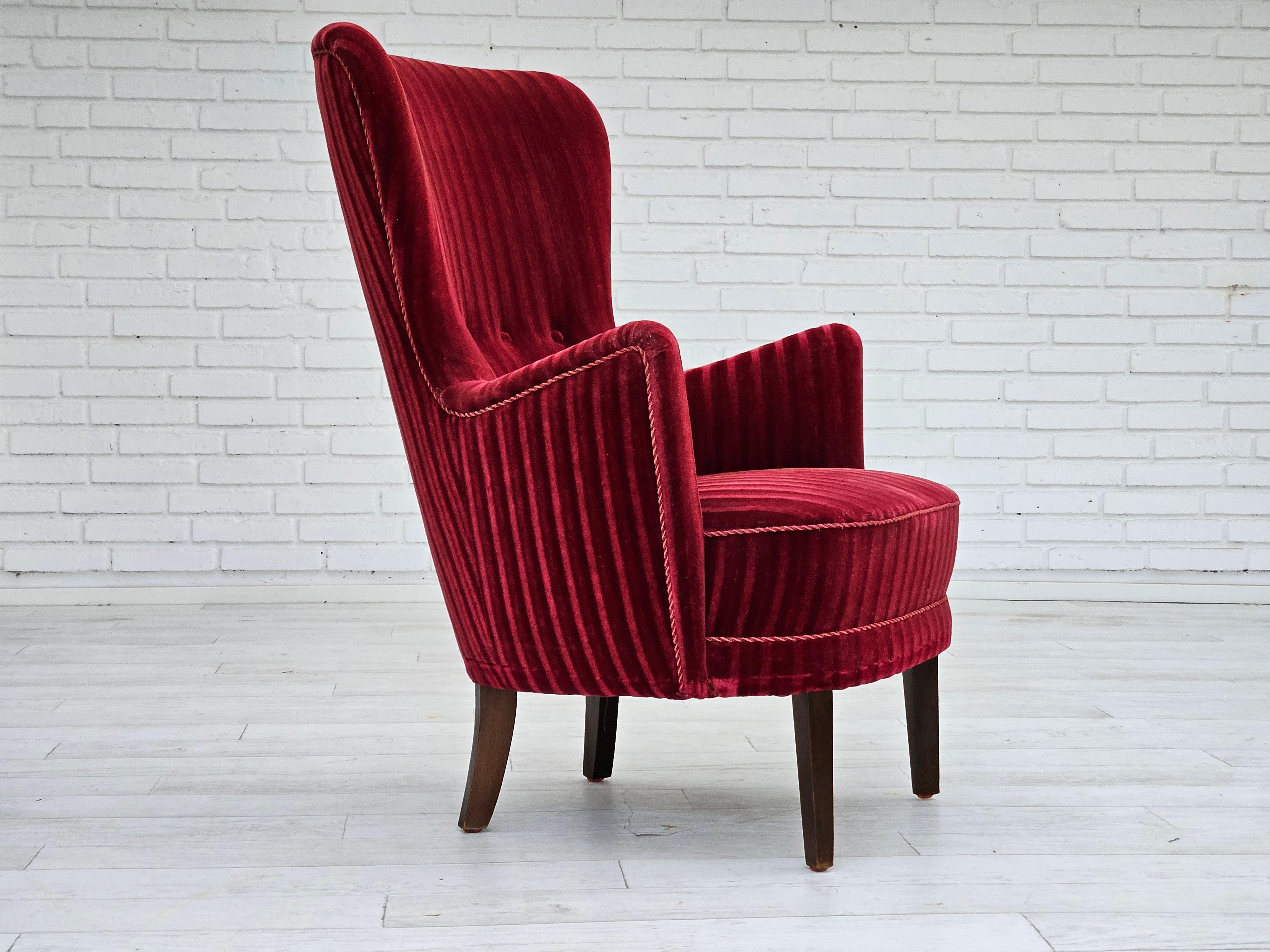 Poltrona danese degli anni '60 in velluto rosso ciliegia. Condizioni originali molto buone: nessun odore, nessuna macchia e struttura stabile. Gambe in legno di faggio, molle nella seduta. Prodotto da un produttore di mobili danese negli anni