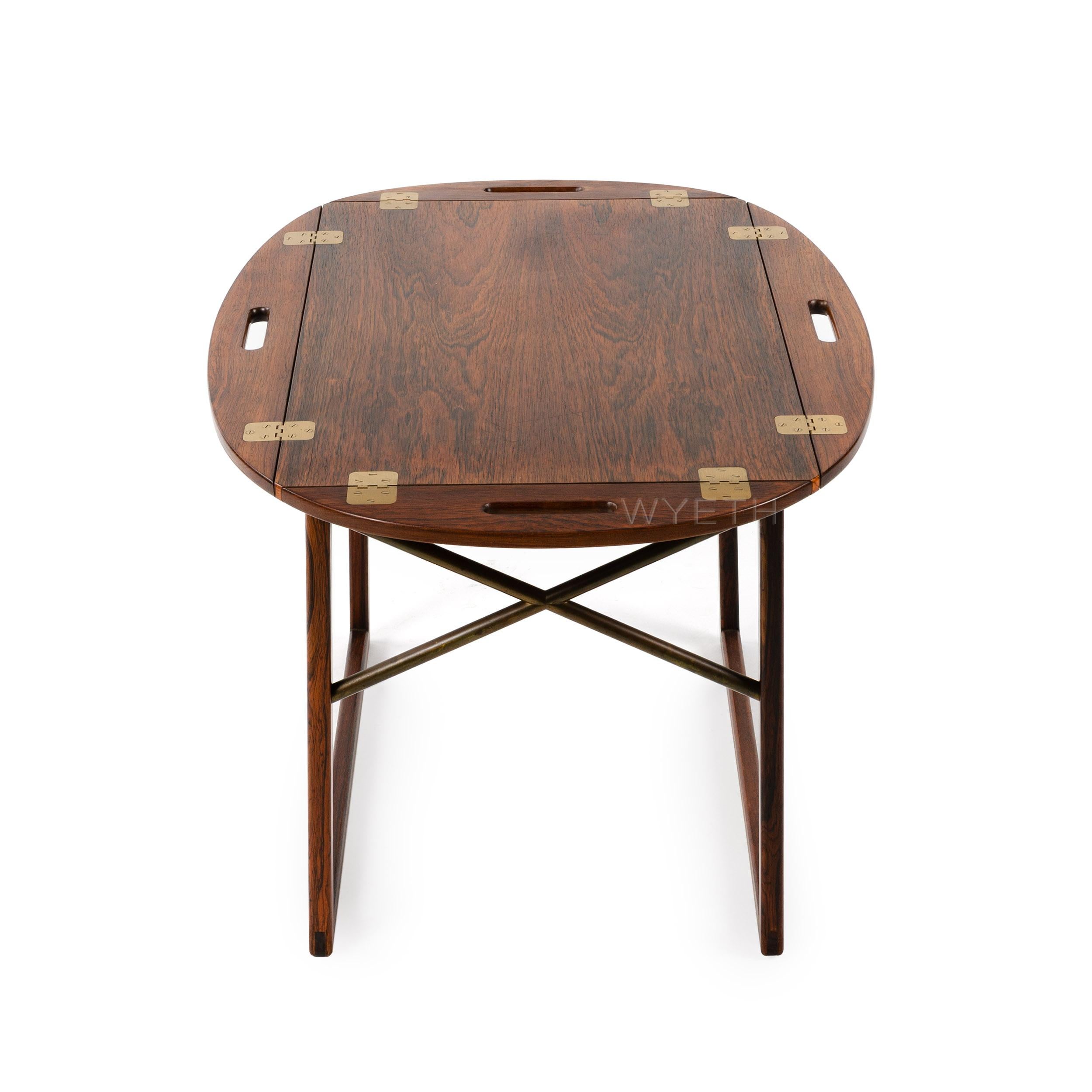 Une table à plateau finement travaillée, en bois de rose, avec un plateau amovible. Les bords articulés en laiton se relèvent pour se transformer en poignées.