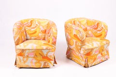 1960s Danish chairs with curved shape, colorful fabric, and elegant skirt.