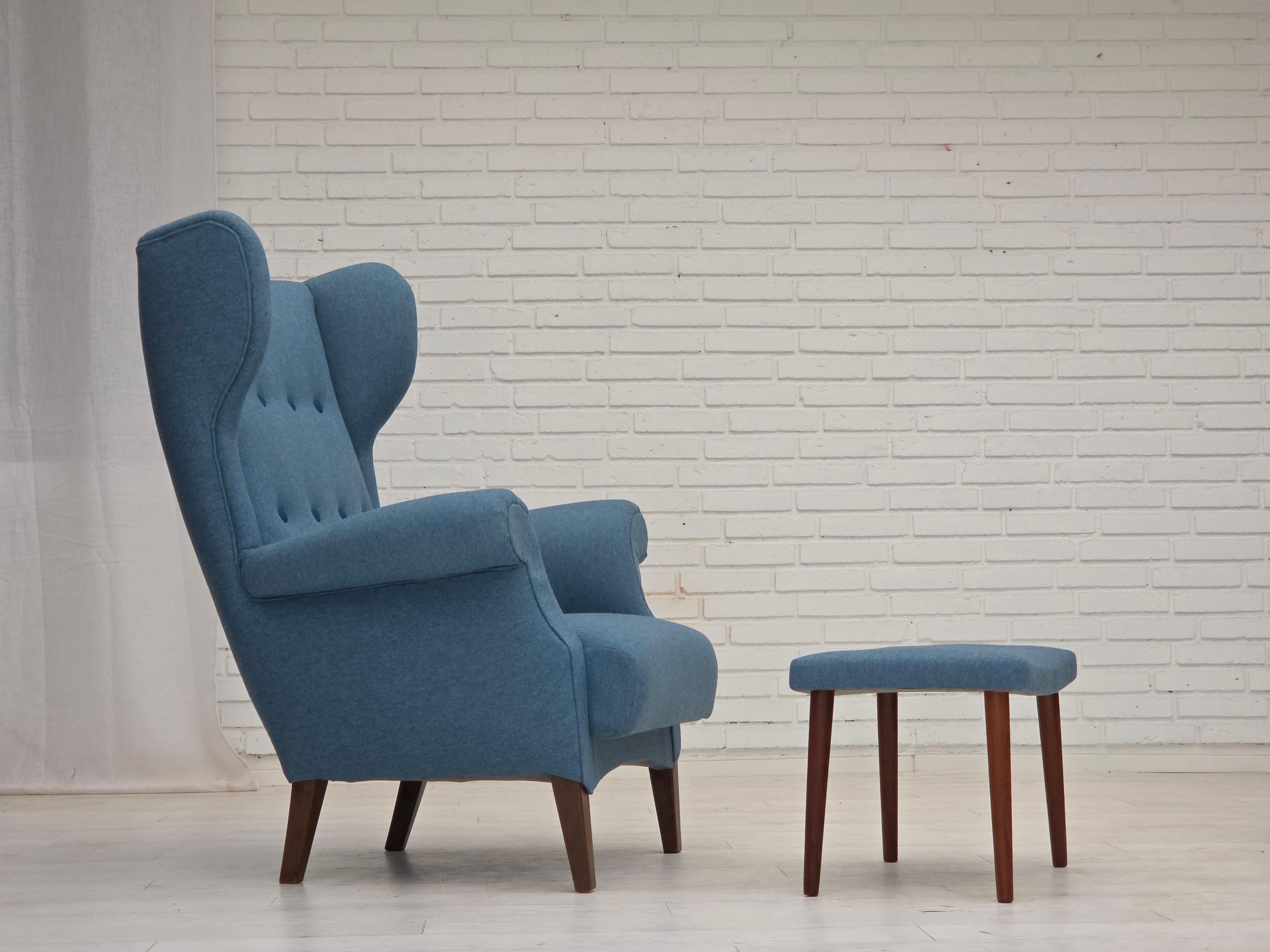 1960s, Danish design by Fritz Hansen. High-backed armchair with ottoman, model 8023. Completely reupholstered, wood refreshed. Upholstered in quality blue furniture wool fabric with dark blue furniture wool buttons. Springs in the seat and back.