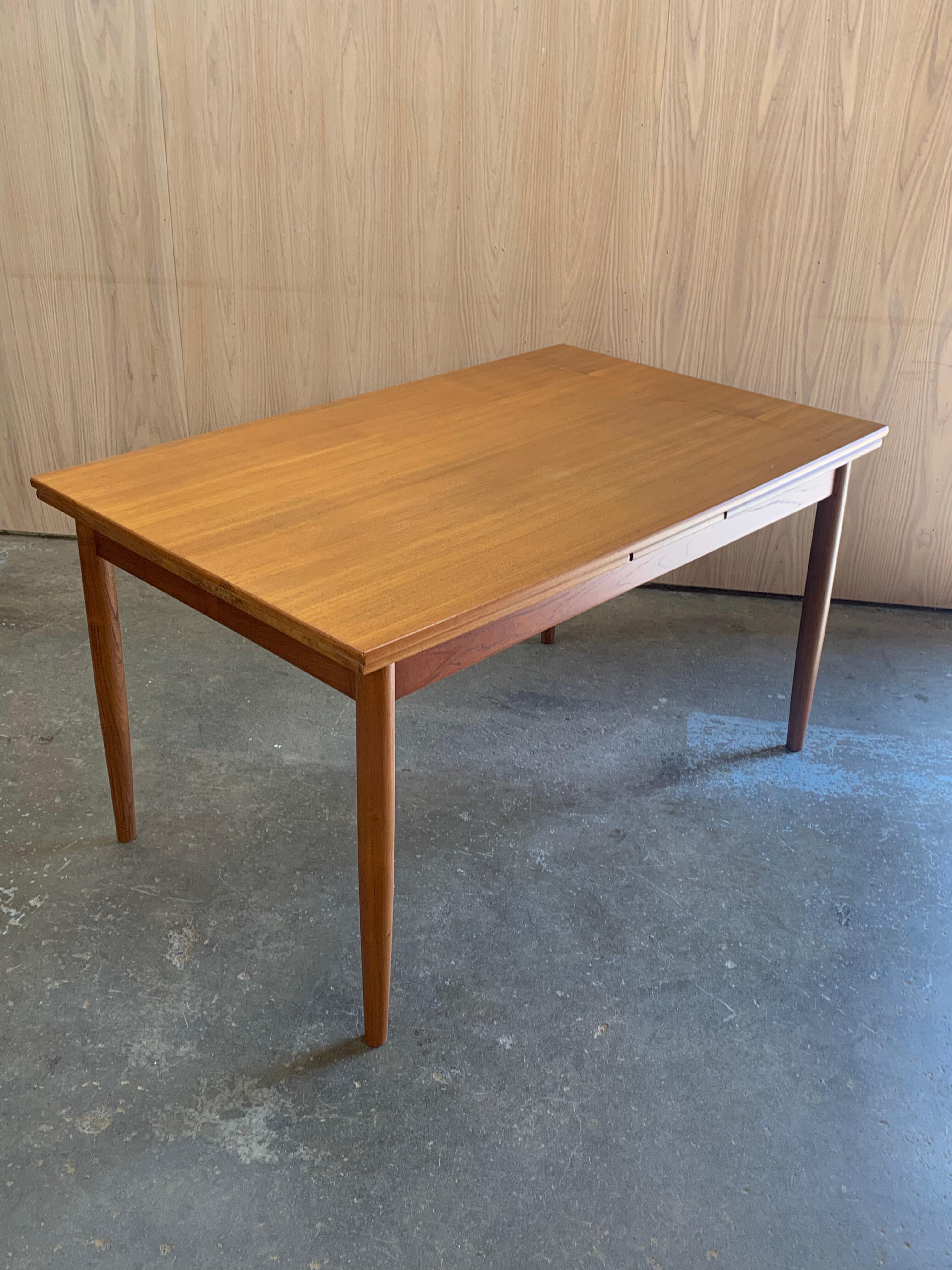 A beautifully balanced example of Danish modernism, this 1960s teak draw-leaf dining table features clean lines, thoughtful proportions, and excellent functionality. The slim profile and tapered legs lend a light, elegant presence, while the two