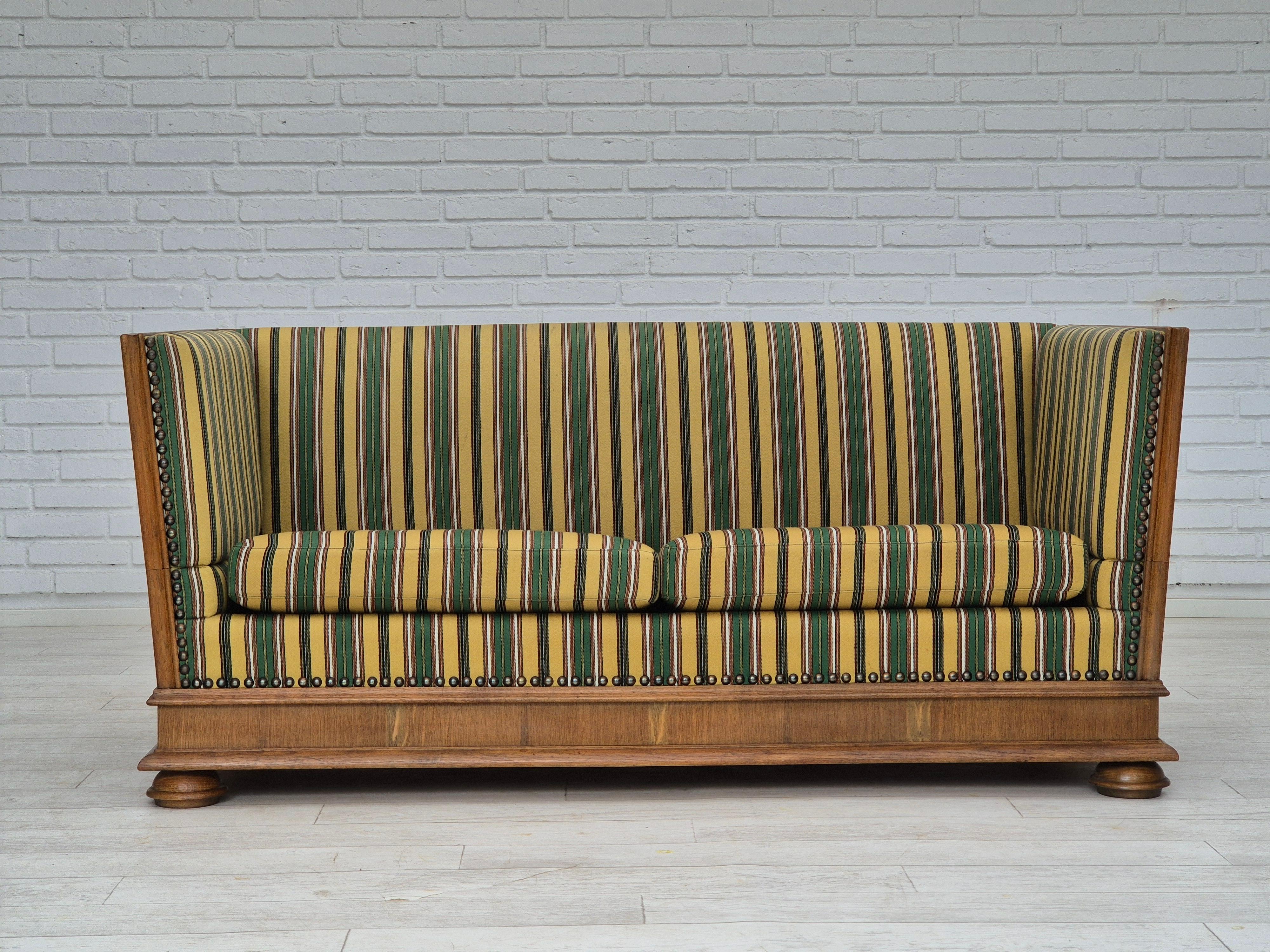 1960s, Danish 2 seater drop arm sofa in original very good condition. Pas d'odeurs, pas de taches, construction stable. Le canapé a été vérifié par un artisan. Meuble en tissu de laine, ressorts dans les coussins d'assise, bois de chêne massif,