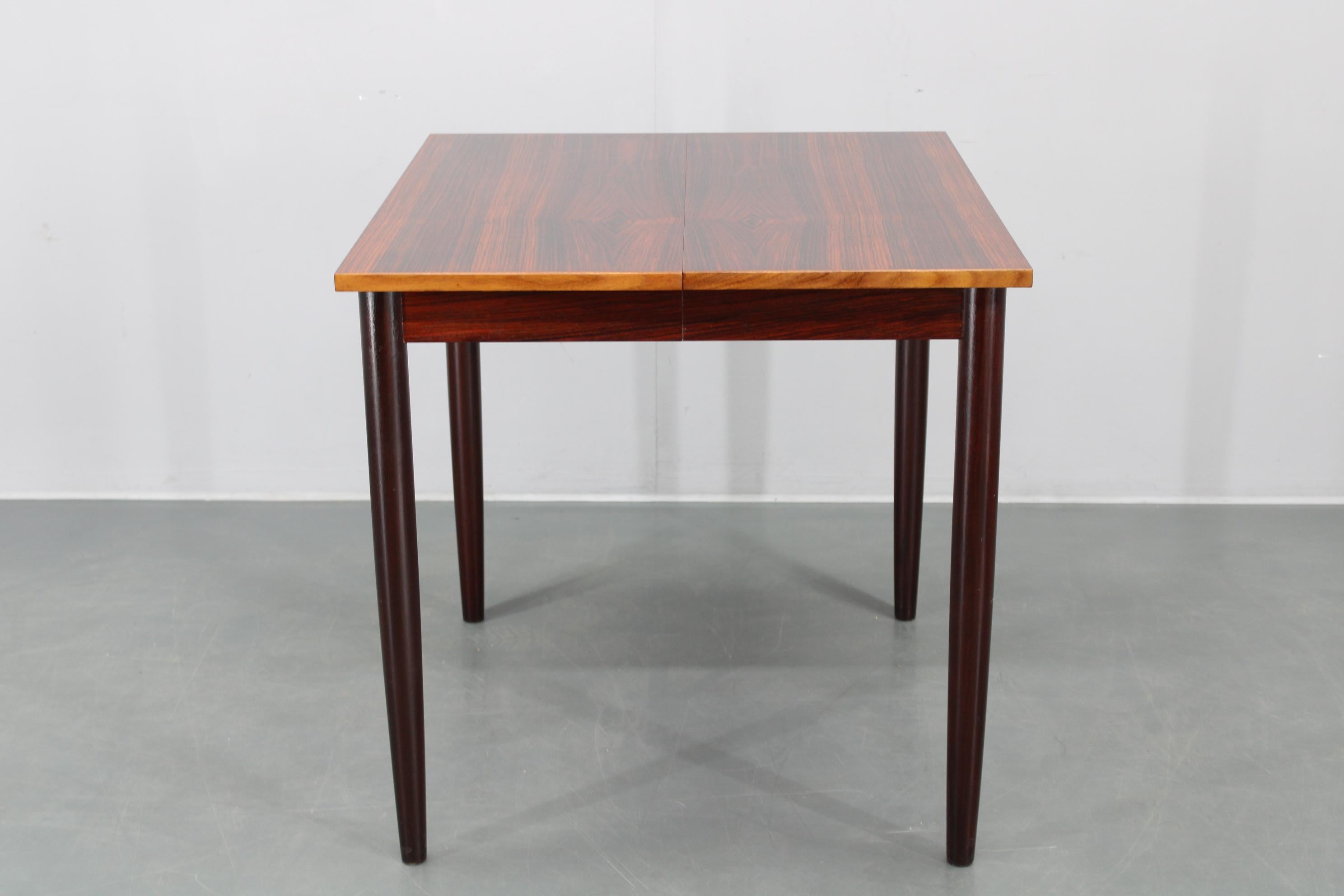 Eleganter dänischer Esstisch aus den 1960er Jahren, fachmännisch gefertigt aus Palisanderfurnier und Massivholzbeinen. 
Dieses vielseitige Möbelstück ist mit vier Verlängerungsflügeln ausgestattet, die es Ihnen ermöglichen, es von einer kompakten