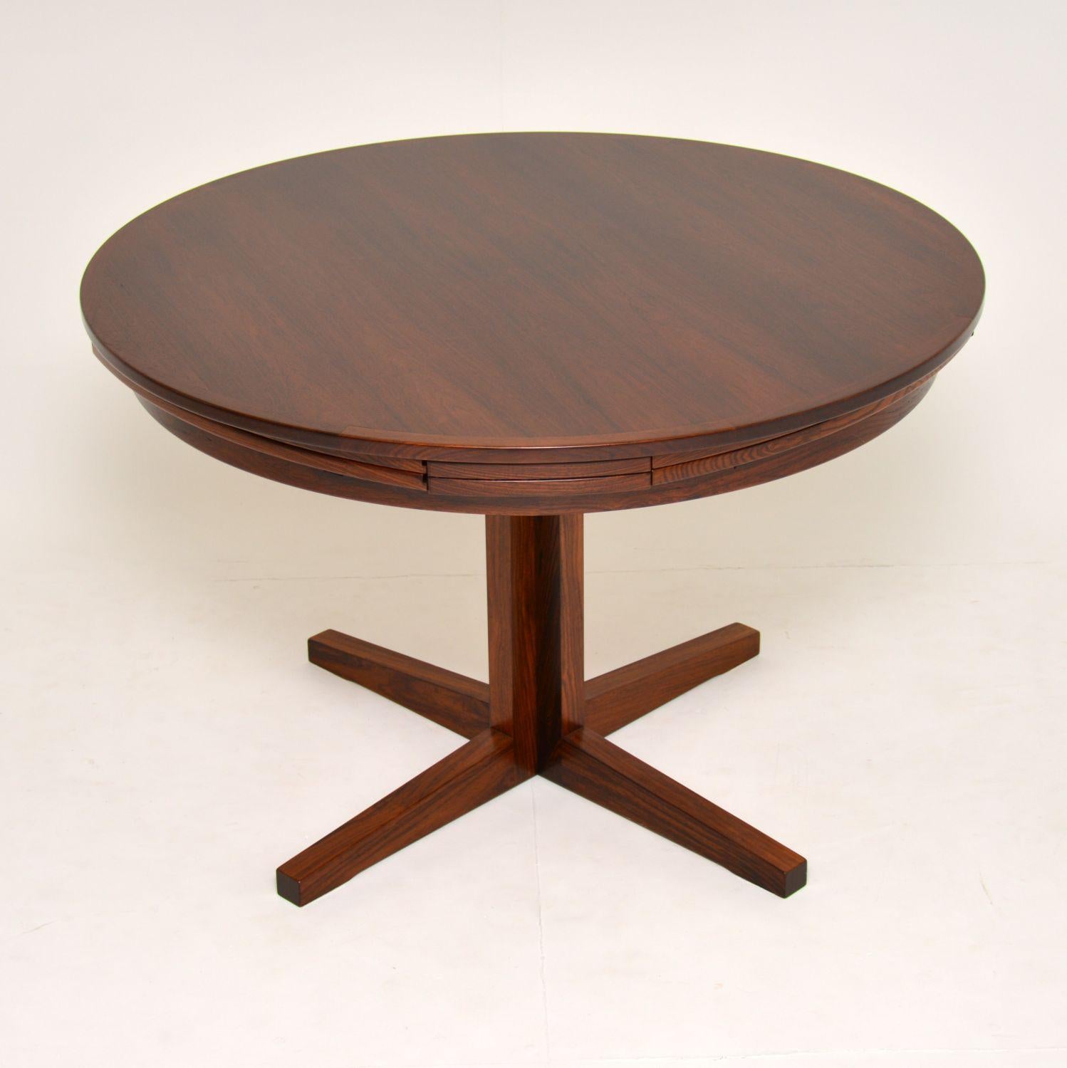 A stunning Danish wooden dining table by Dyrlund, this is the famous flip flap lotus table, it dates from the 1960s. This is a very rare version, with a single column pedestal and a slightly smaller top and leaves than normal. The quality is