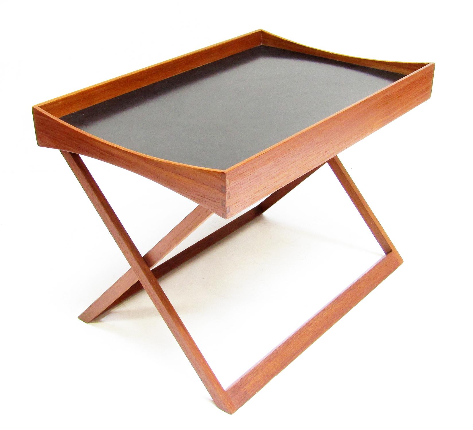 A 1960s Danish folding side table by Torsten Johansson for Bo-Ex. 

With one surface in teak and the other in black formica, the top can be reversed depending on its use.

Its design has a clear campaign or colonial influence. It can be disassembled