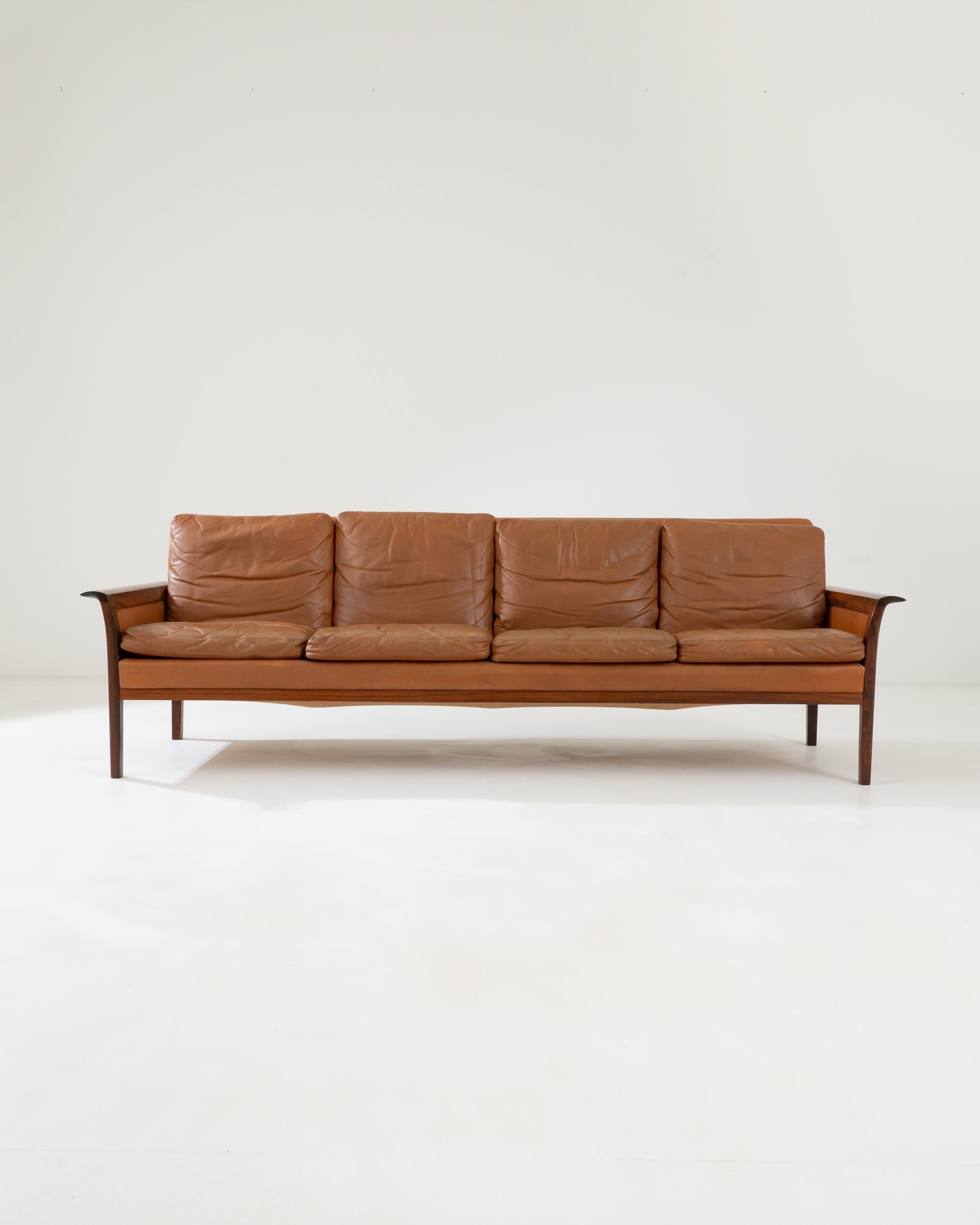 A four-seat leather sofa created in 1960s Denmark by Hans Olsen. This elegant, yet inviting sofa, stretches out, offering luscious seating space for four sitters. Created by experimental furniture designer, Hans Olsen, this particular sofa artfully