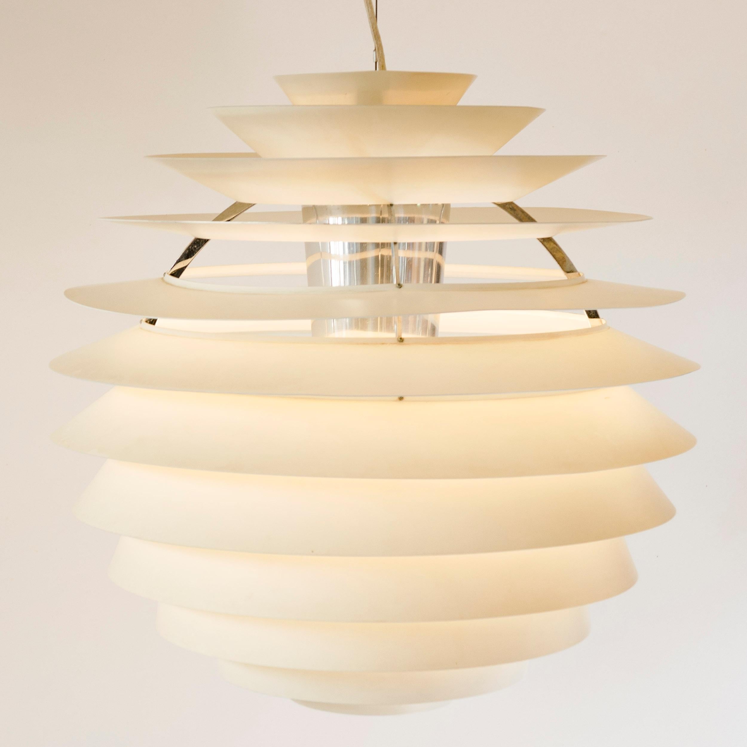 A chandelier comprised of concentric white enameled aluminum louvres, emanating from a central internal reflector.