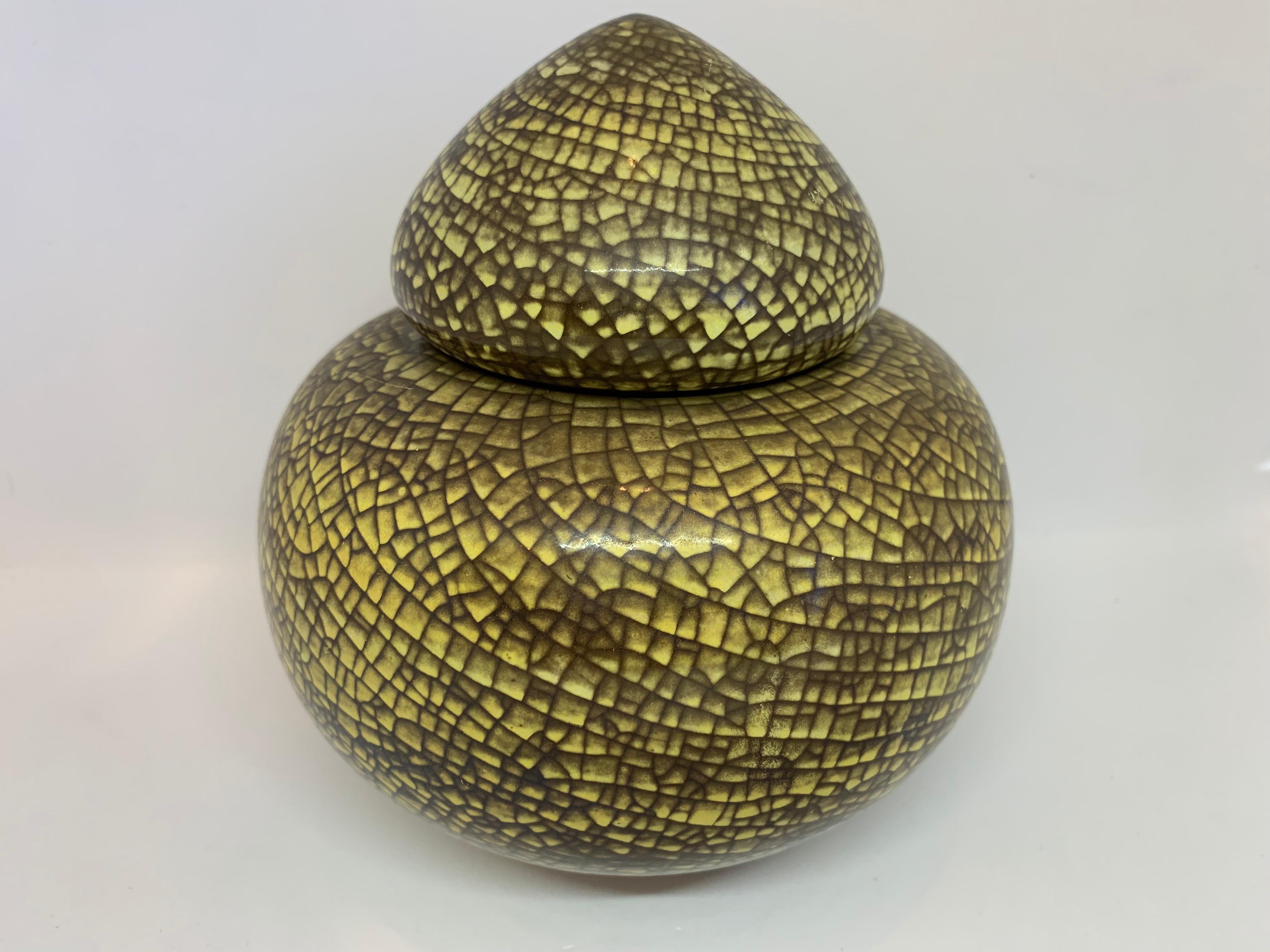 An unusual vintage, 1960s, Michael Anderson & Son, ceramic urn or lidded vase. The yellow urn is overlaid with a crazed green crackle effect design over its surface. A rounded conical lid fits loosely in the top. The base is iridescent with the