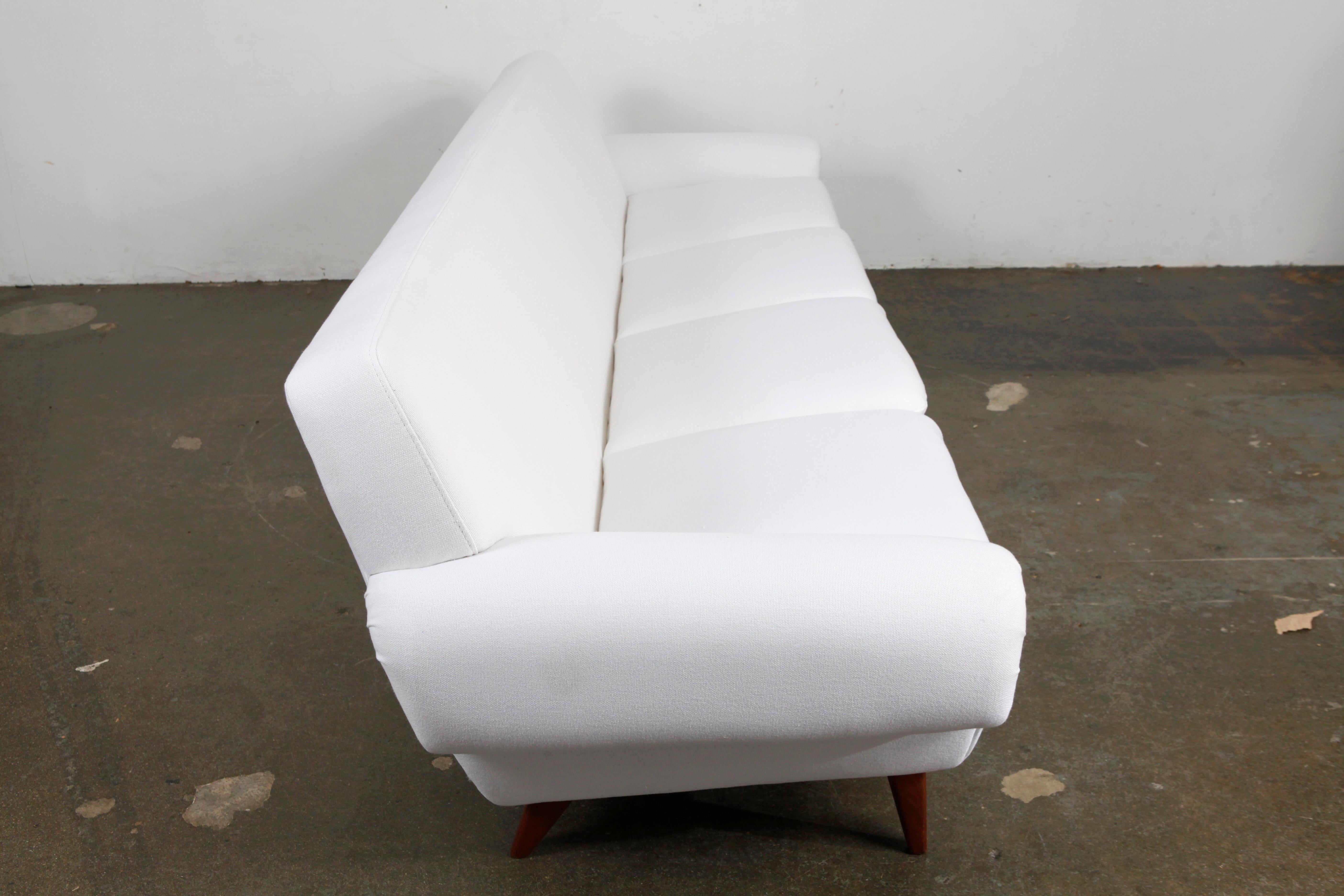 Beautiful four-seat loose seat and back cushion midcentury Danish sofa newly upholstered in a white fabric that has been treated with a non-toxic stain resistant coating, Denmark, circa 1960s.