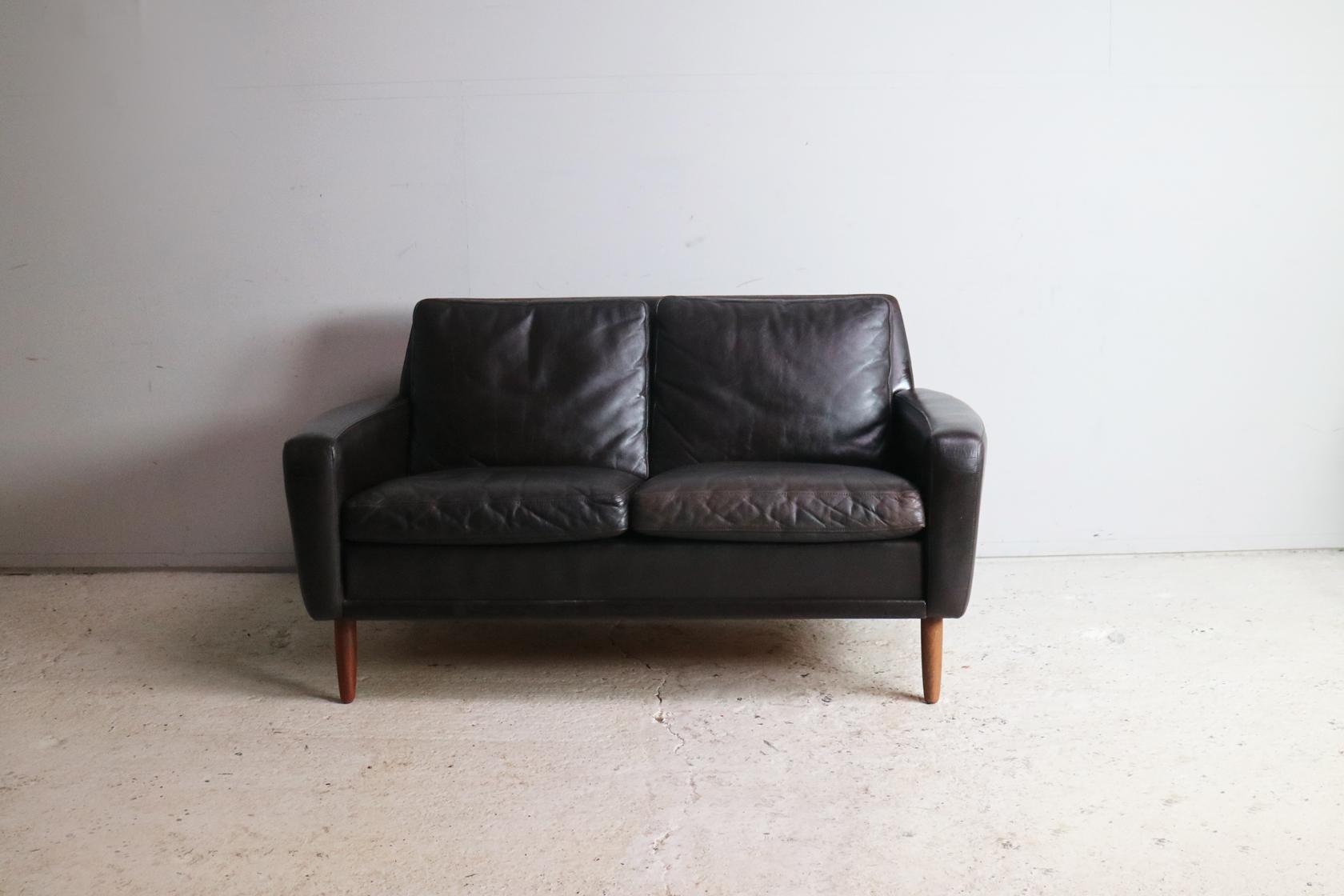 A lovely Danish Mid-Century Modern sofa with a great shape with subtly curved arms. Upholstered in the original very dark brown (virtually black) leather with turned teak feet.
  