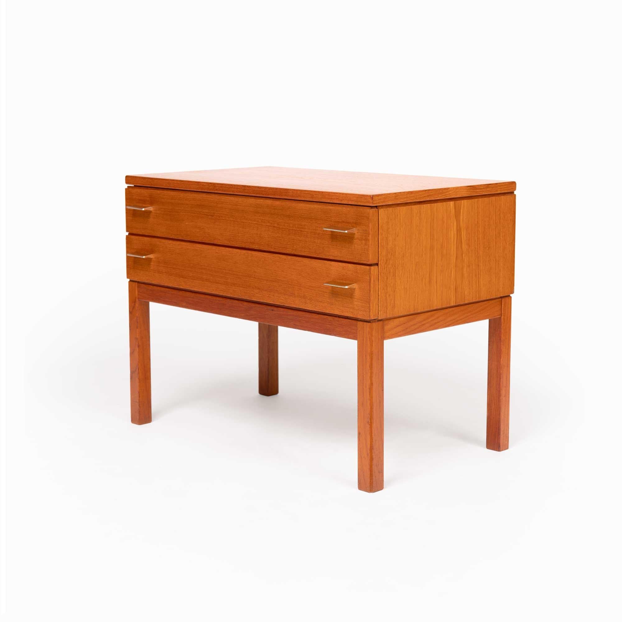 Diese schöne Kommode aus dänischem Teakholz im Vintage-Stil weist eine beeindruckende Teakholzmaserung auf. Seine kompakte Größe macht ihn zur idealen Wahl für die Verwendung als Akzentmöbel, Eingangstisch oder Nachttisch. Diese Kommode zeigt die