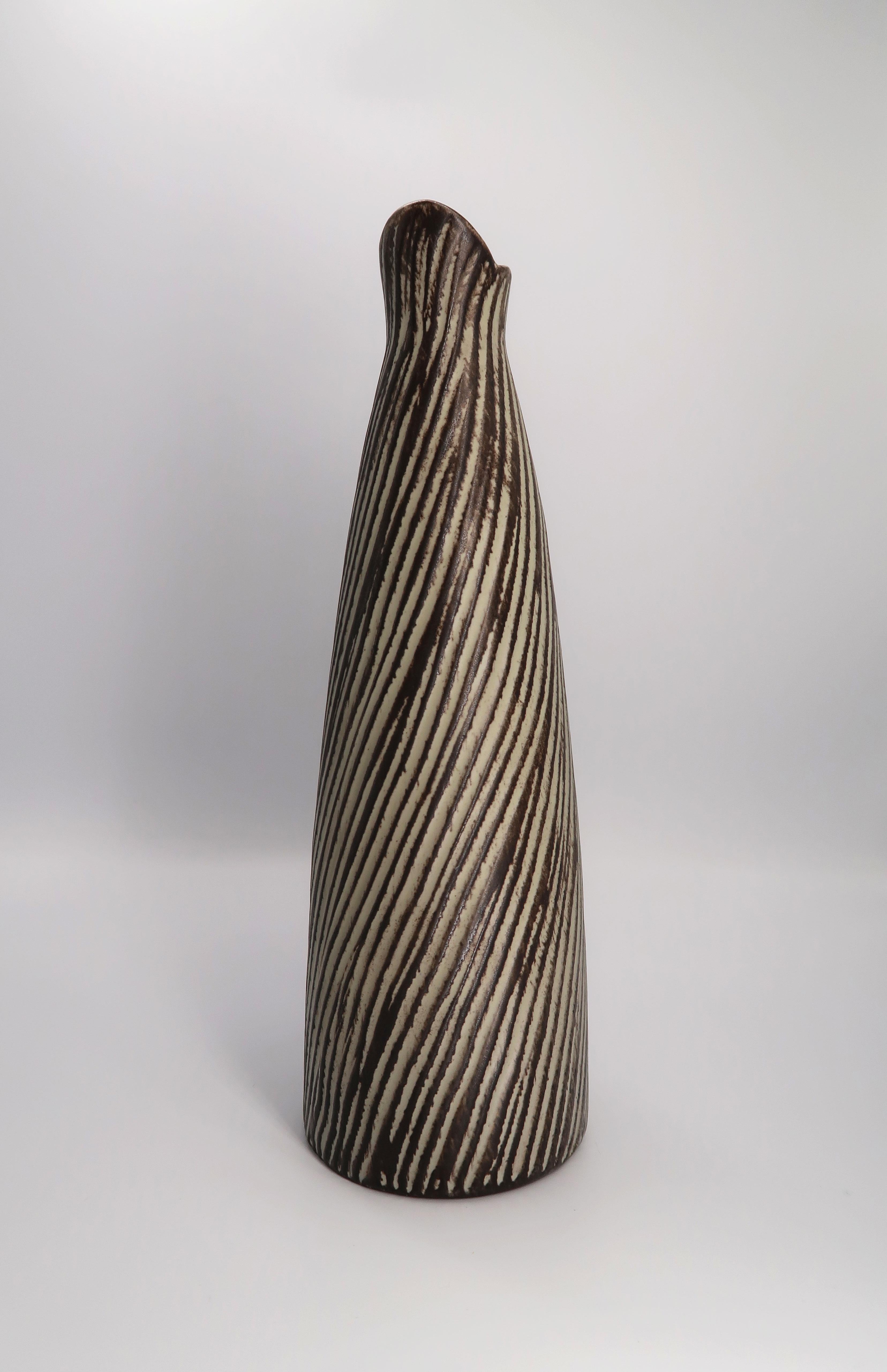 Danish Mid-Century Modern ceramic vase/pitcher with bamboo handle attached with bast. Grey and dark brown glazed relief stripes run diagonally across the whole vase. Designed and handmade by Danish ceramic artist Jette Helleroe. Signed under base.