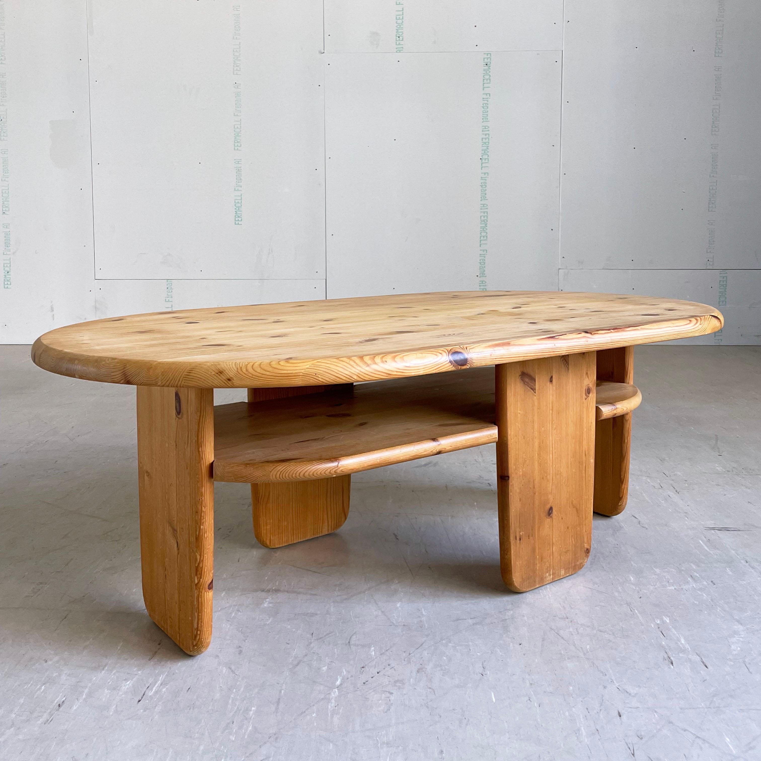 1960's Danish modern oval shaped coffee table in solid pine, attributed to Rainer Daumillerand. 
Solid pinewood construction. Scandinavian minimalism in Brutalist style, with tabletop, magazine shelf and legs. Lovely wood grain and coloring.