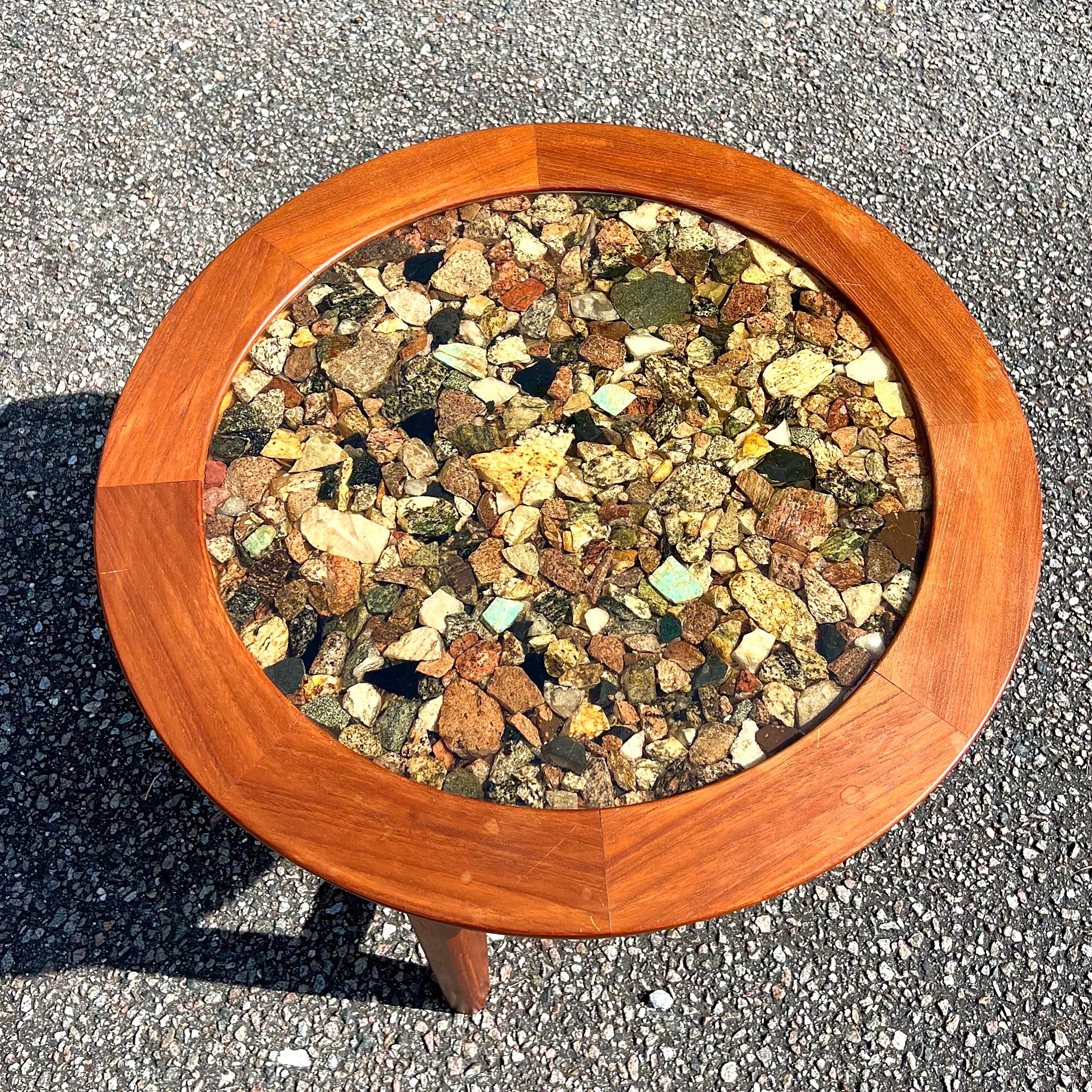 A gorgeous solid teak frame table with an X base stretcher and a beveled teak top.  The stones inside the resin are not polished and when you flip it over, you can see and feel the different specimens.   There is definitely turquoise and obsidian