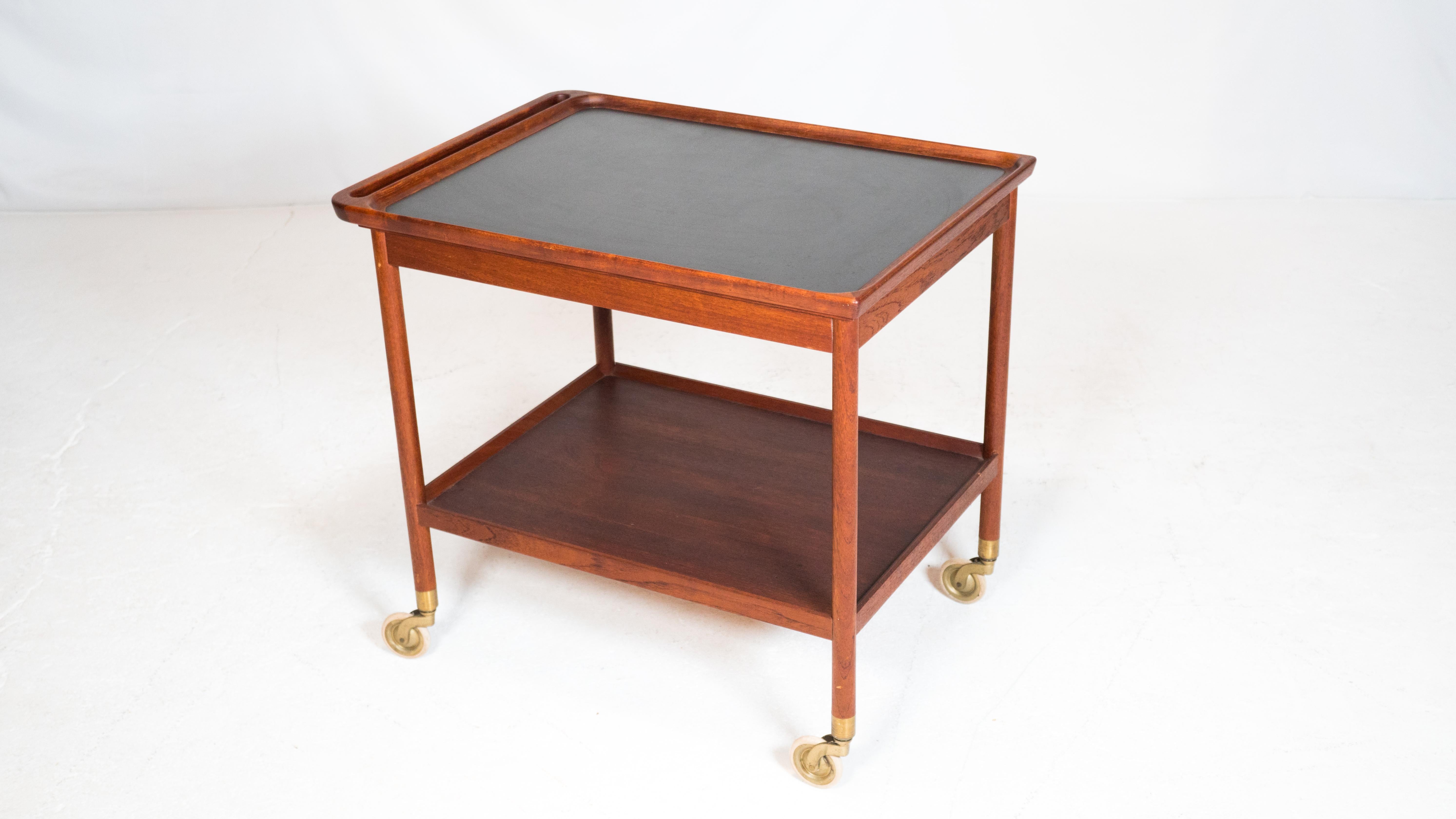 Danish modern teak bar cart or serving trolly by Ludvig Pontoppidan, circa 1960s. Old-growth teak construction with rich woodgrain details. Black laminate top, brass casters. Two tiered design with ample storage and seamless, integrated handle. Good