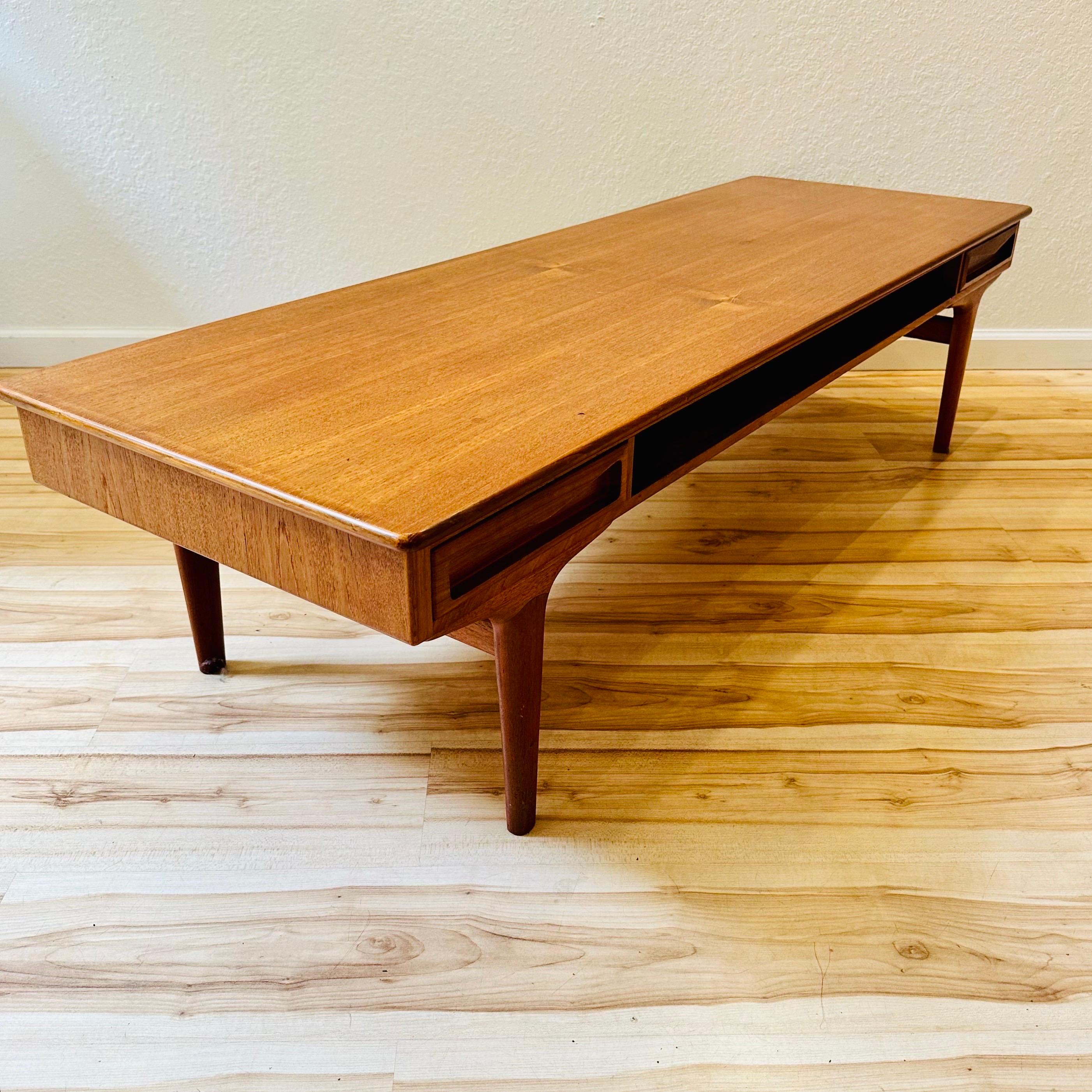 1960s Danish Modern teak coffee table by Johannes Andersen. A timeless piece that showcases the elegance and simplicity of mid-century Danish design, the table has two drawers that can be accessed from either side. Crafted from rich teak wood, this