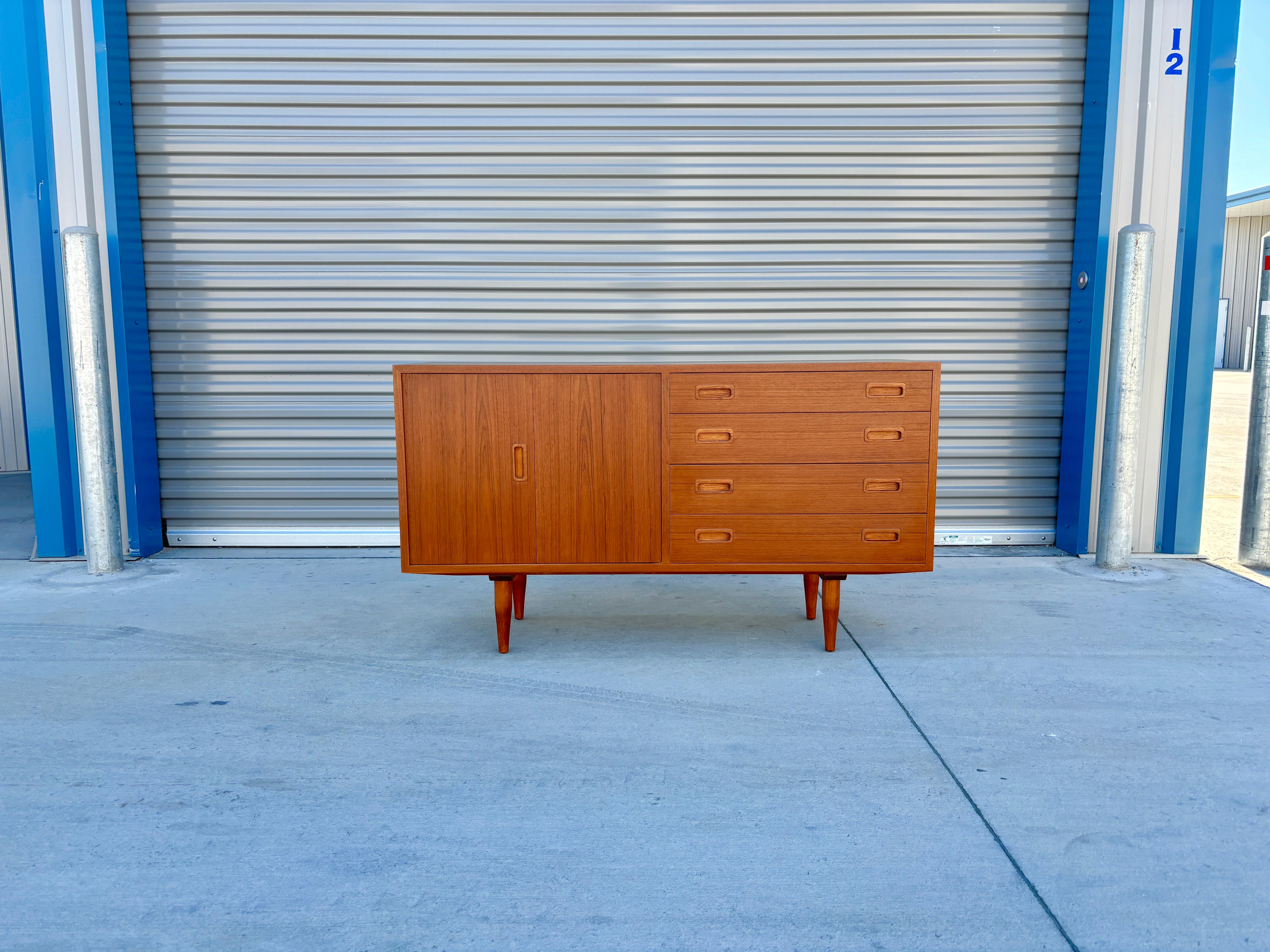 Aparador moderno danés de teca diseñado por Carol Jensen y fabricado por Hundevad & Co. en Dinamarca hacia la década de 1960. Este impresionante aparador tiene un armazón de teca, que desprende una estética refinada y elegante. La pieza está