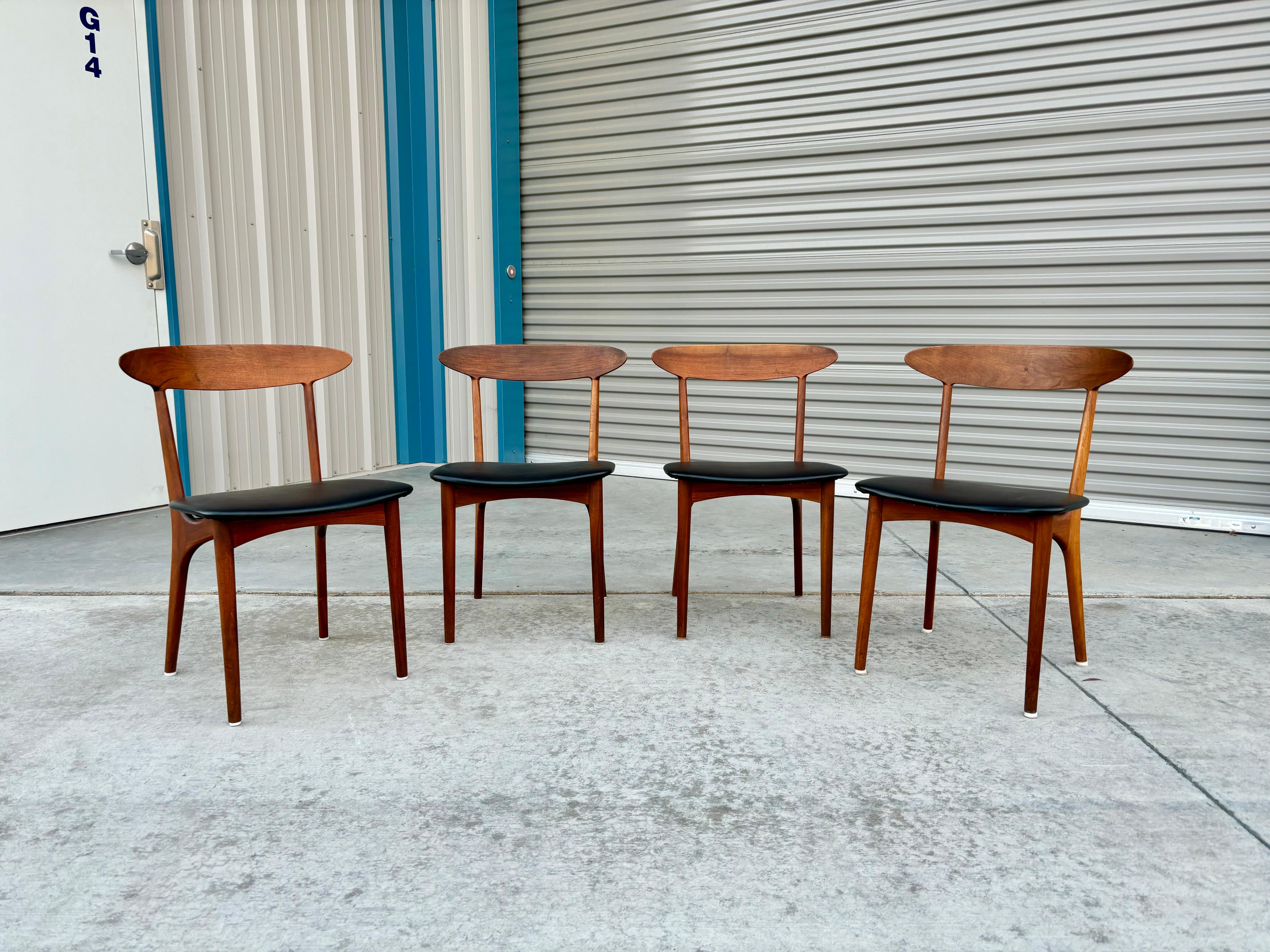 Danish modern teak dining chairs designed by Kurt Ostervig and manufactured by Brande Møbelindustri in Denmark circa the 1960s. These dining chairs feature a black leather upholstery that sits on top of a beautiful teak frame. What makes this set