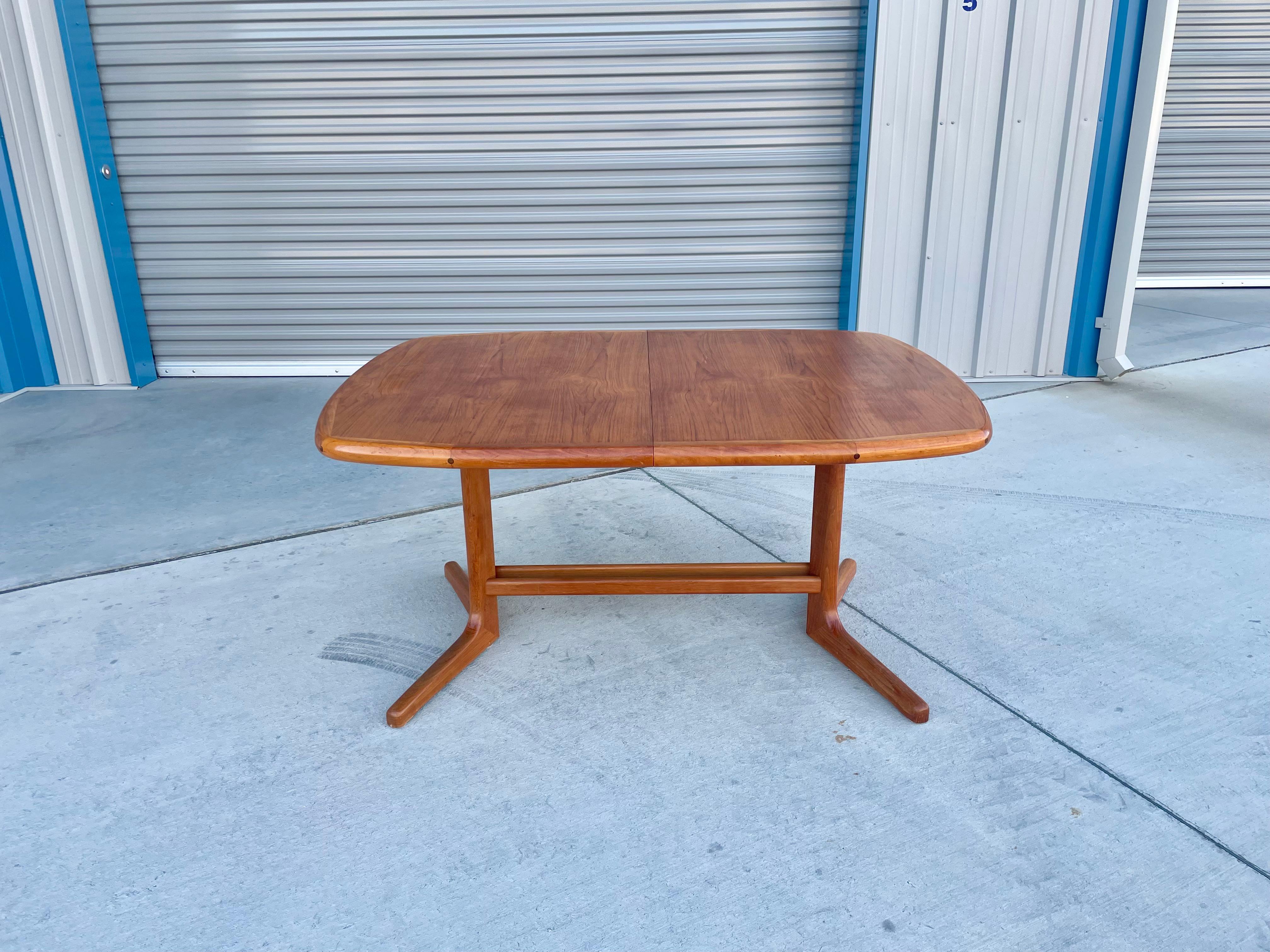 Danish modern teak dining table designed and manufactured in Denmark circa 1960s. This amazing dining table features an oval shape top that sits on top of a teak base. The table comes with two leaves, letting you extend the table, creating plenty of