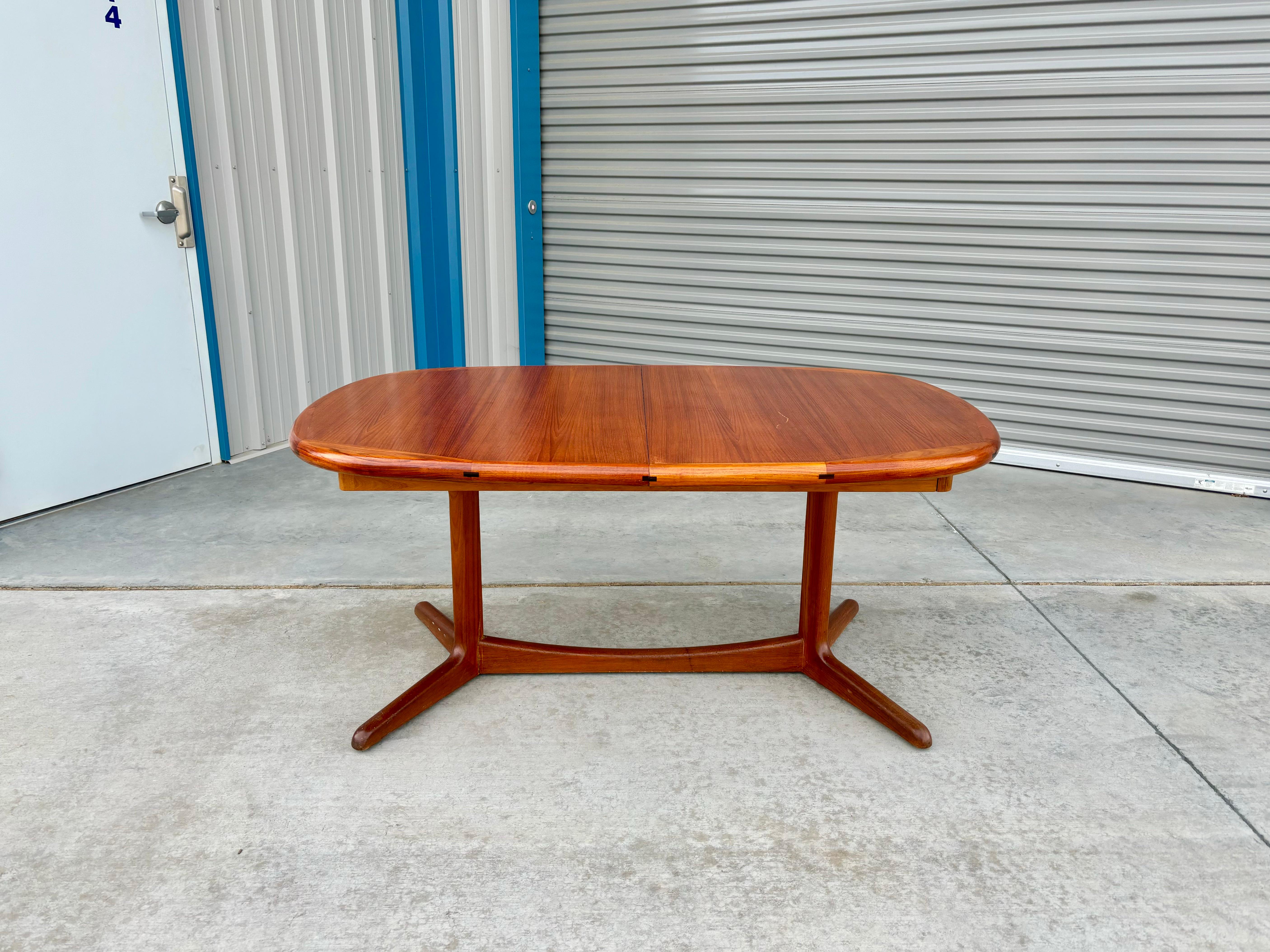 Danish modern teak extendable dining table designed and manufactured in Denmark circa 1960s. The table features a sleek teak frame perched atop an elegant teak pedestal, exuding a perfect balance of form and function. The table is not only a visual