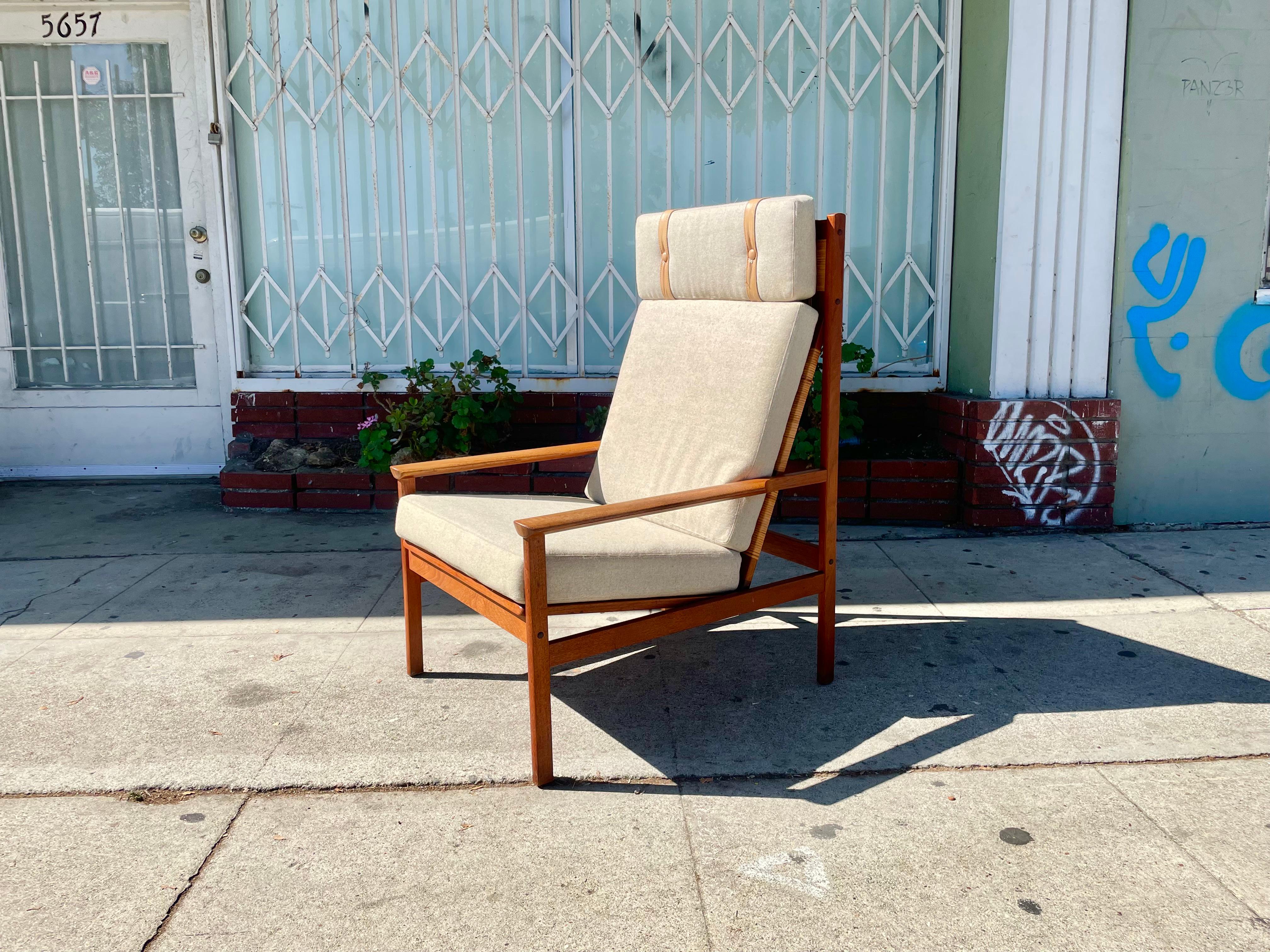 Danish modern teak lounge chair designed by Hans Olsen for Juul Kristensen in Denmark circa 1960s. This beautiful high-back chair features a teak frame with a cane-back finish, providing comfort and style guaranteed to draw anyone's attention. You