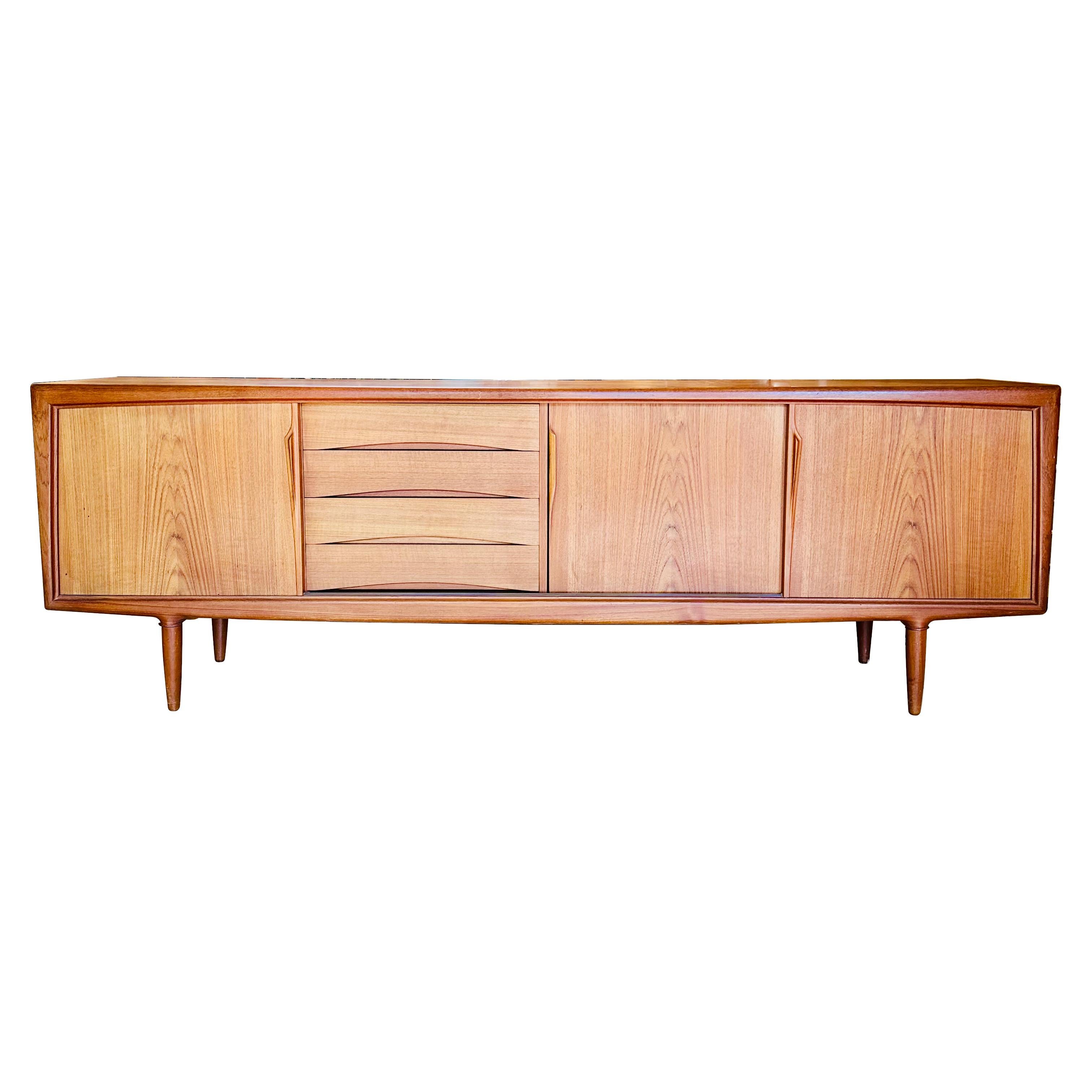 1960s Danish Modern Model 13 teak cabinet/credenza designed by Gunni Oman for Axel Christiansen Oder (ACO) Mobler. A striking example of mid-century Danish design, the credenza has sliding doors, sculpted pulls, and four felt-lined drawers. The top