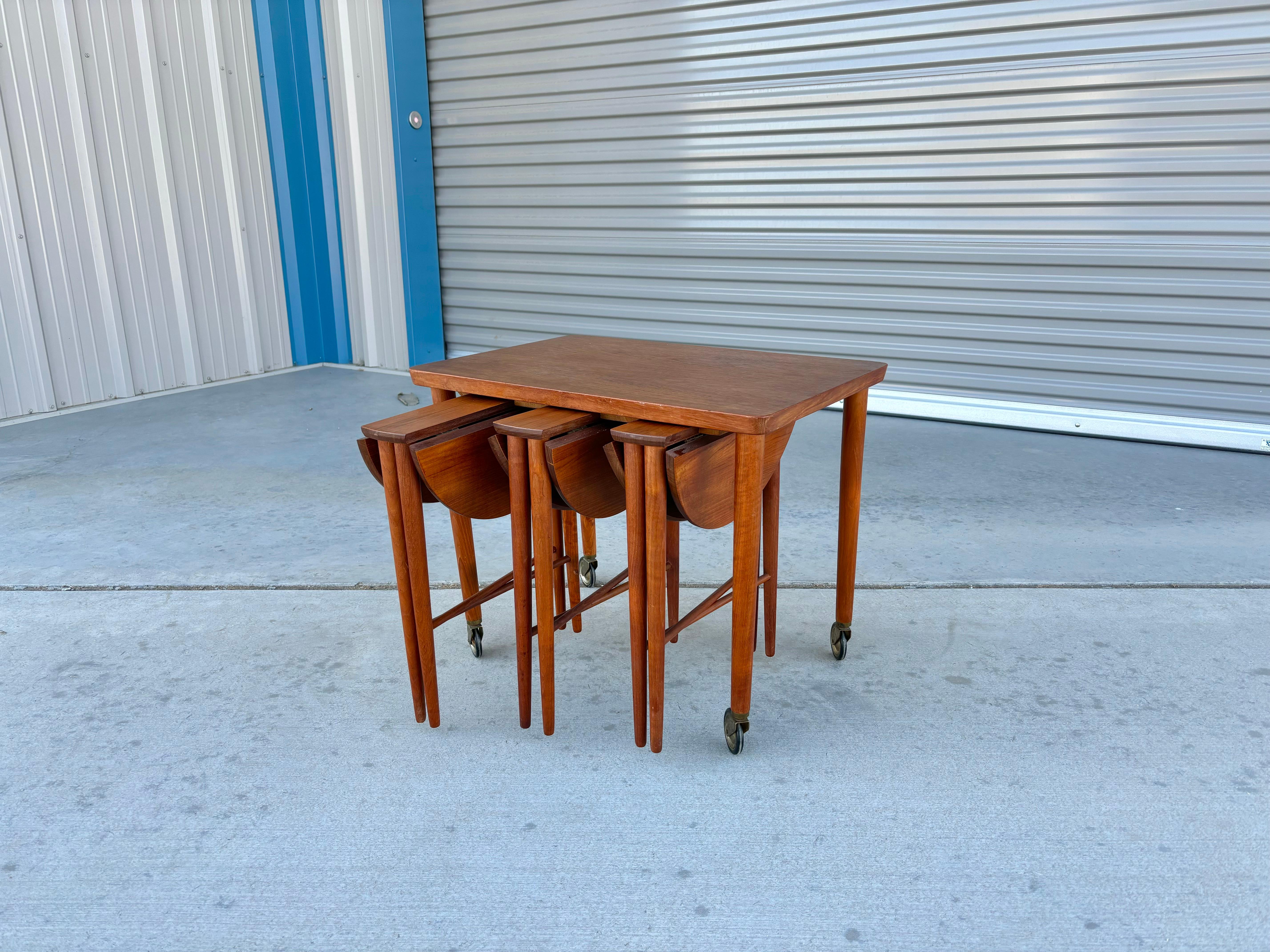 Danish modern teak nesting tables designed by Paul Hundevad in Denmark circa 1960s. The sleek teak frame and unique design make this set a must-have for any mid-century modern enthusiast. What's impressive is that the main table has three smaller