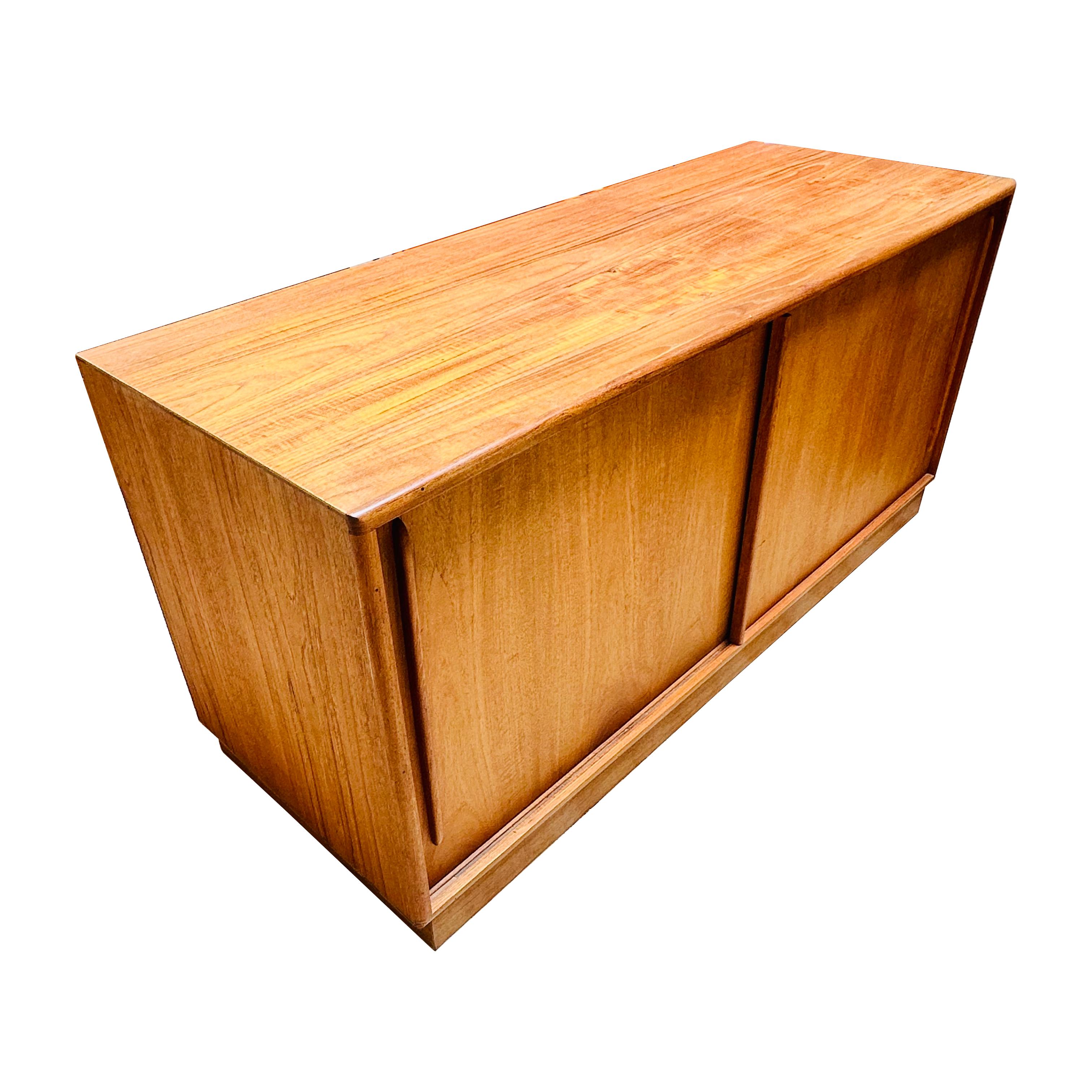 1960s Danish Modern teak stereo credenza. The credenza has two sliding doors and a retractable shelf, and an electrical outlet.. The lower left is divided for LP storage. In excellent condition.

Width: 57.25 in / Depth: 21.25 in / Height: 27.25 in