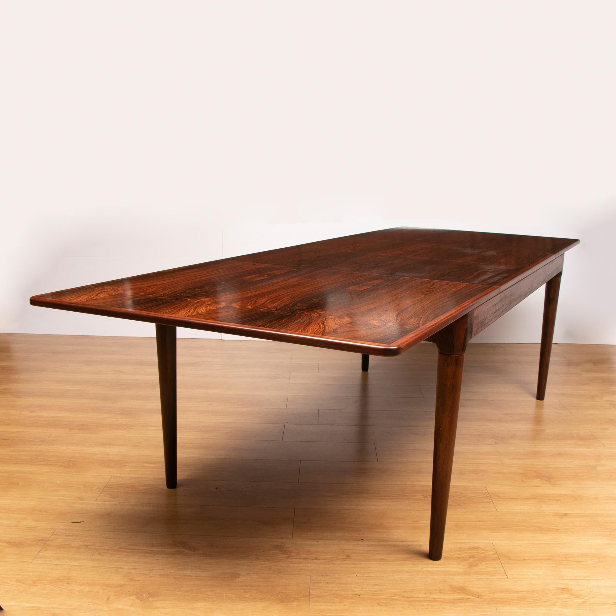 1960s Danish Mogens Kold for Arne Hovmand Olsen Brazilian rosewood two-leaf extendable dining table. The two separate leaves can be stored underneath the table when not in use. The solid Rosewood legs screw into the table and are removable when the