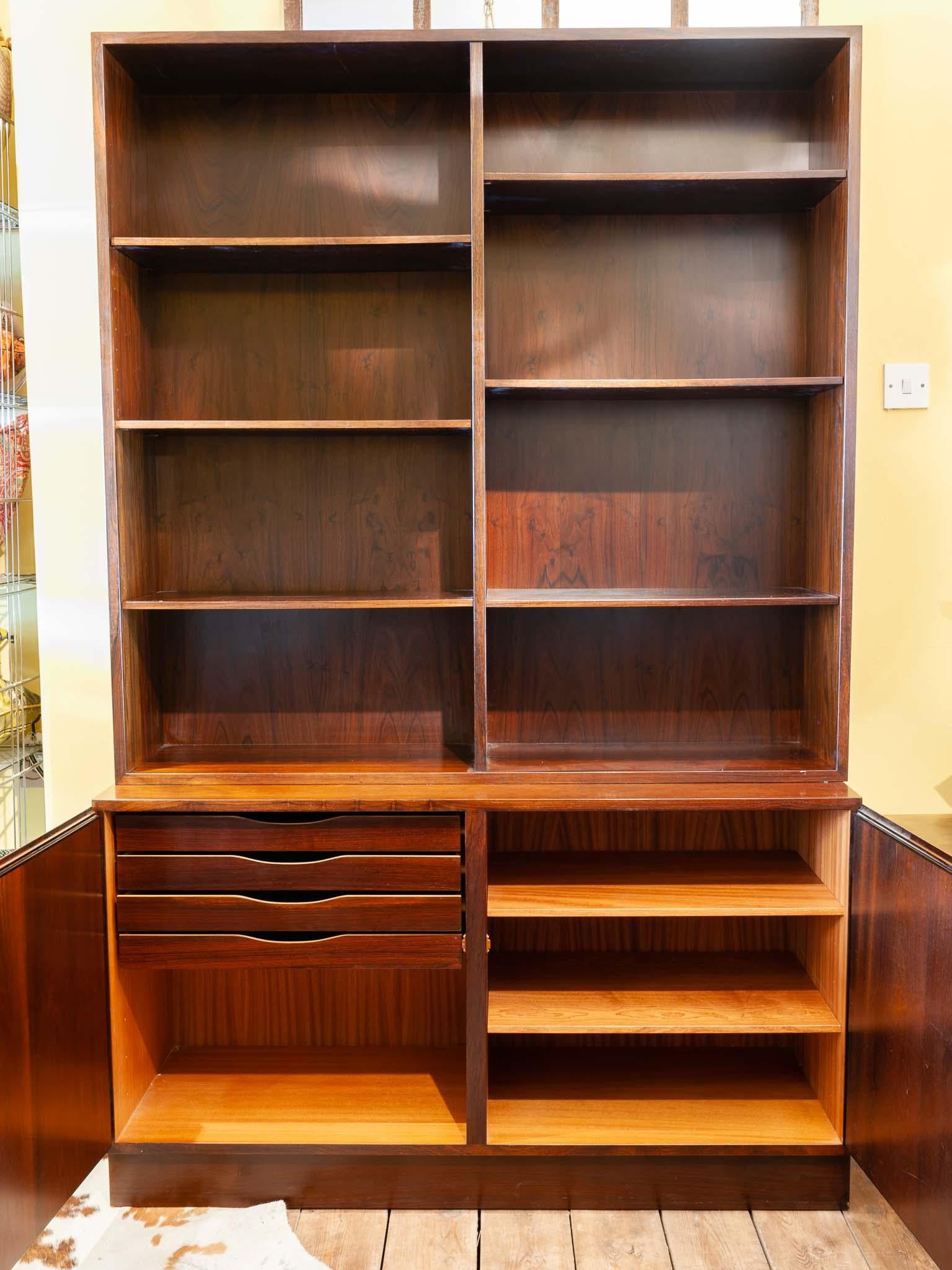 Vintage 1960s rosewood veneer bookshelf/shelving unit with two storage cupboards manufactured in Denmark by Omann Jun. Model No.4. The shelving unit features six adjustable shelves (with two spares) that sit on a double storage unit below. The