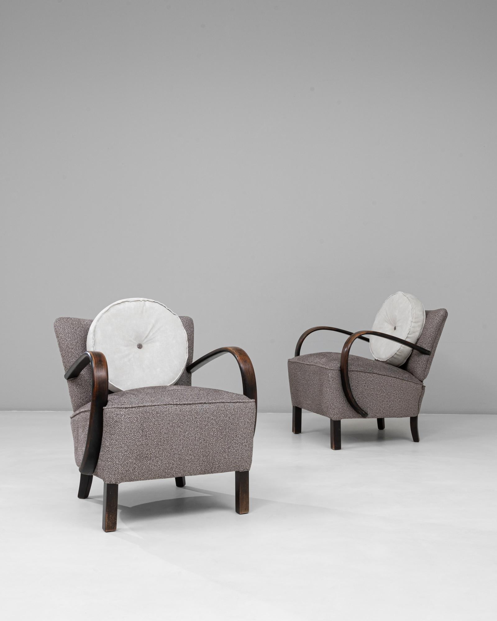 This 1960s Danish pair of Art Deco upholstered armchairs reflects the refined craftsmanship and fluid design synonymous with mid-century Scandinavian style. Each chair features elegantly curved wooden arms in a dark, rich finish that contrasts
