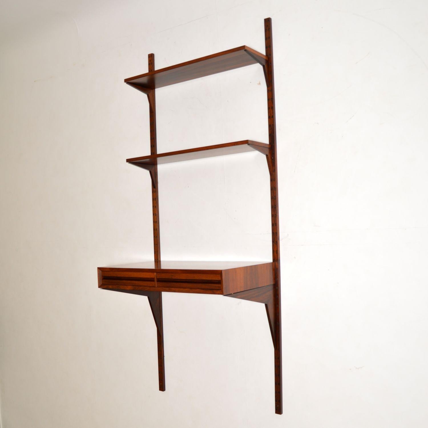 A stunning Danish rosewood wall unit dating from the 1960s, this is the royal shelving system designed by Poul Cadovius. This consists of two full size rails, two shelves, one writing desk and all the corresponding chevron supports. This is a lovely
