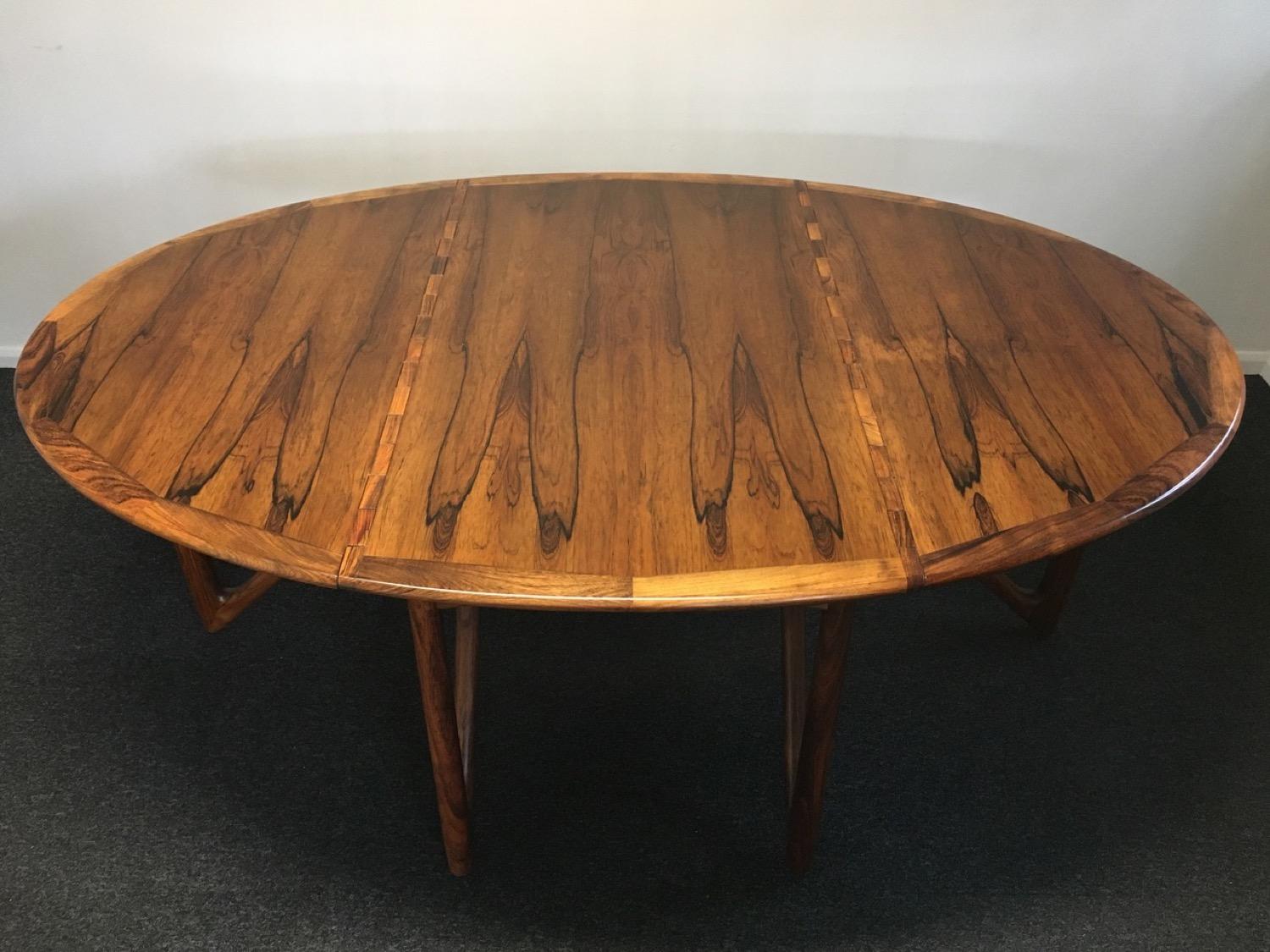 A 1960s Rosewood gate-leg drop-leaf dining table designed by Kurt Ostervig and manufactured by Jason Møbler. The table is beautifully restored with the most incredible grain and patina. The table is oval when both leaves are fully extended over the
