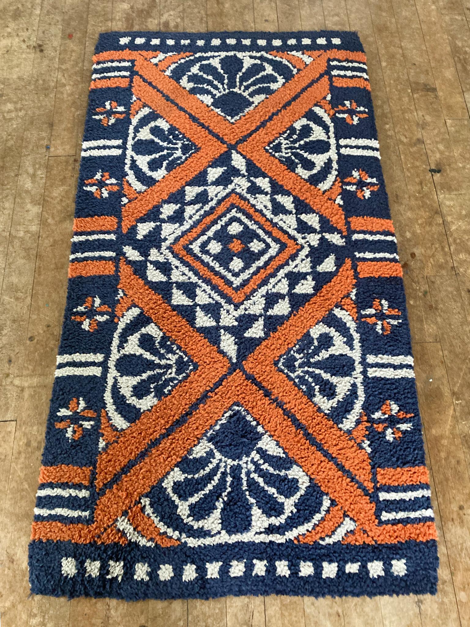 This Danish rya rug is comprised of thick pile wool in a palette of dark blue, orange, and white. The design is a bold composition of geometric shapes and florals.

Dimensions:
5' 9