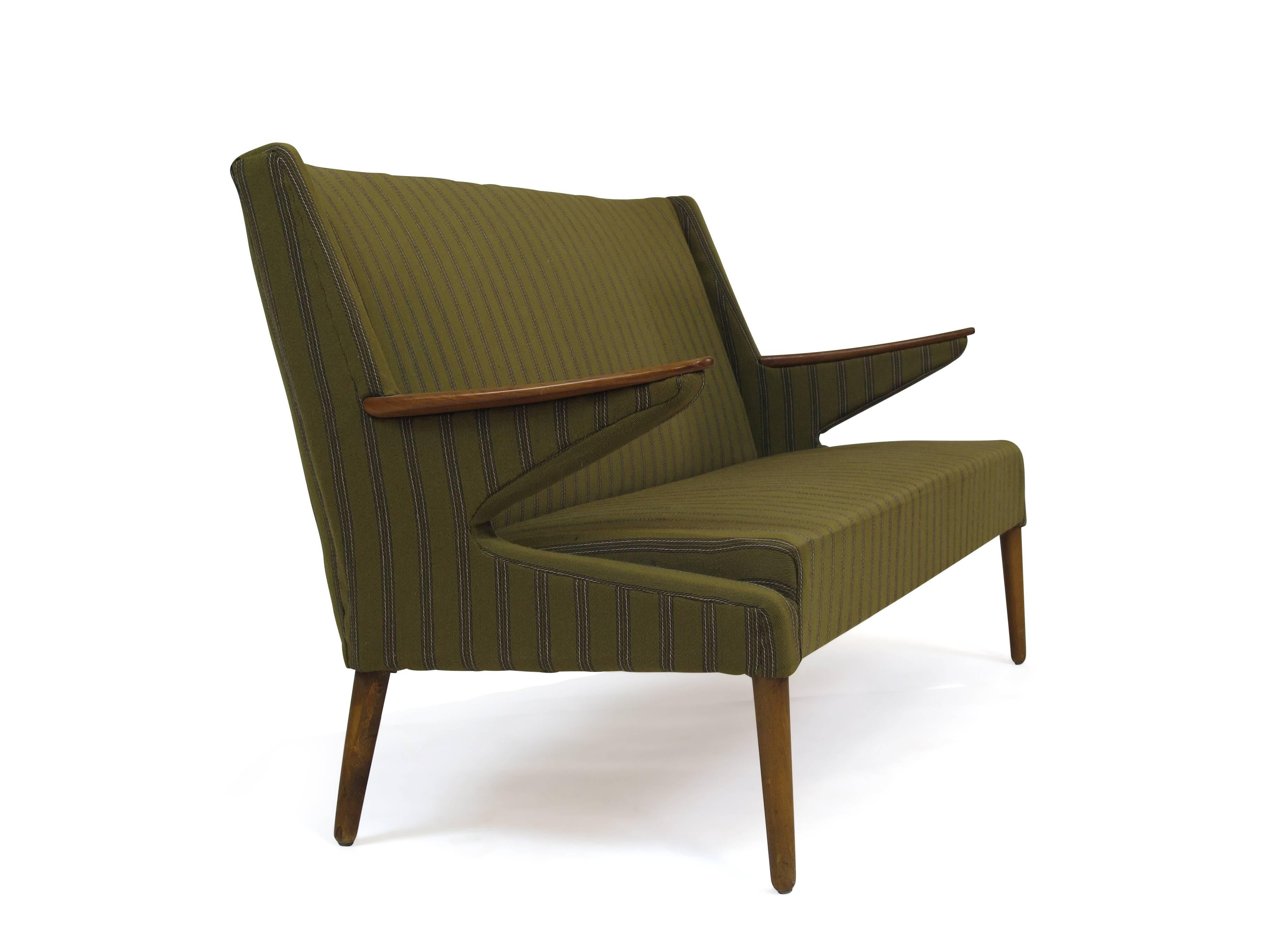 Midcentury Danish sofa upholstered in the original green wool fabric with angled teak arms, raised on turned legs.