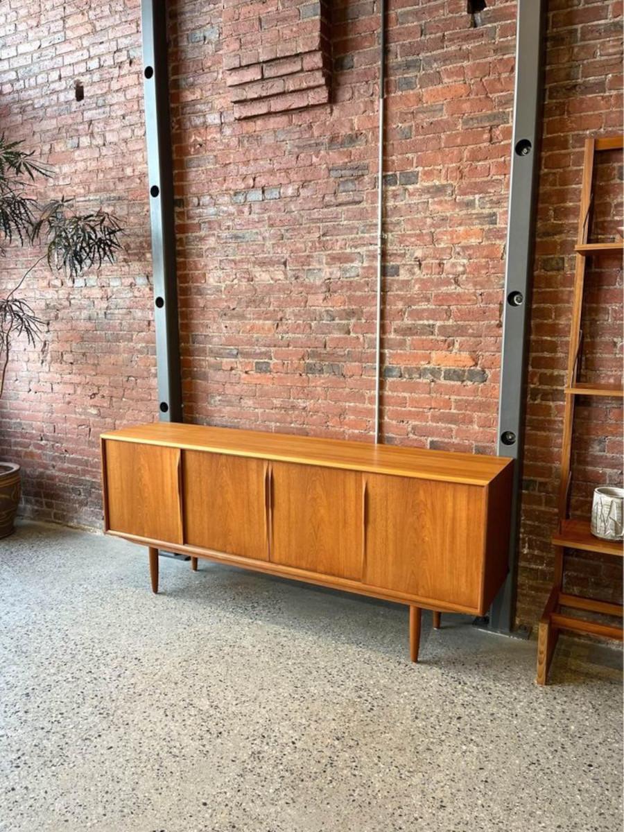 Step into the realm of mid-century modern sophistication with this iconic sideboard from the 1960s, designed by Axel Christensen for ACO Møbler. Crafted from high-quality teak, this timeless piece features sculpted handles seamlessly integrated into