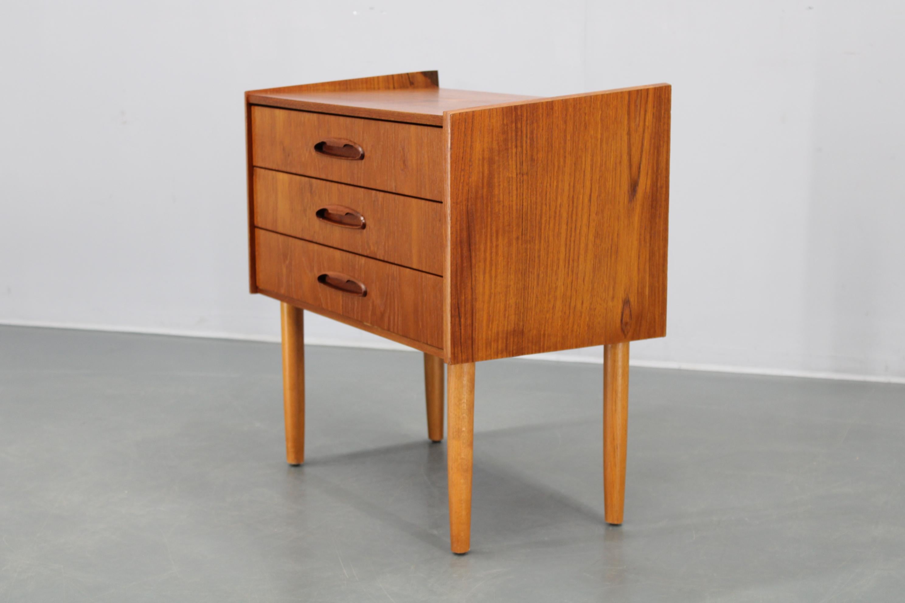 Classica cassettiera danese degli anni '60, parzialmente ristrutturata, con impiallacciatura in teak, maniglie in teak massiccio e gambe in faggio. Questo mobile compatto è perfetto per camere da letto, ingressi o soggiorni, grazie alle sue linee