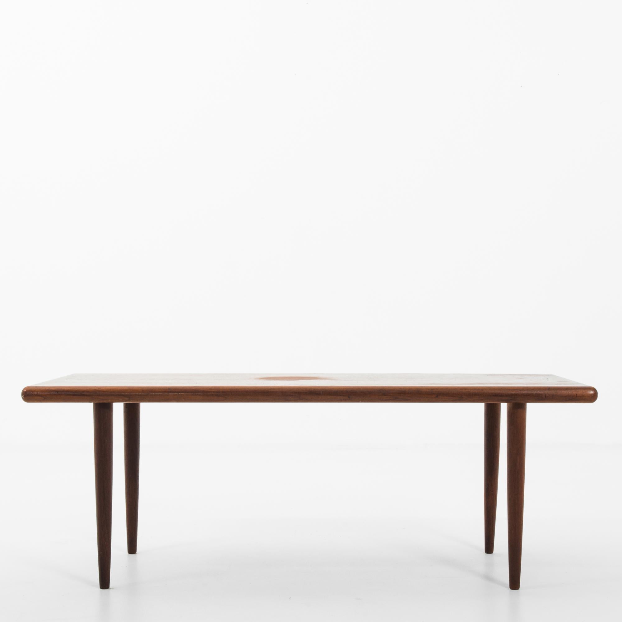 A teak coffee table from Denmark, circa 1960. With its bold, curving lines and combination of glass on top rich, dark wood, this table is classic Scandinavian modern. Chic, sleek and practical, this table is waiting to host all the art and travel
