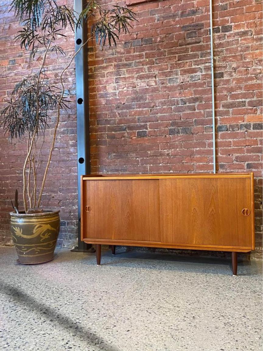 Rare and delightful teak credenza from Denmark, crafted by Jydsk Møbelfabrik in the 1960s. This charming piece boasts two effortlessly sliding doors, a convenient internal drawer, and adjustable shelving. Meticulously restored by our team, it is in