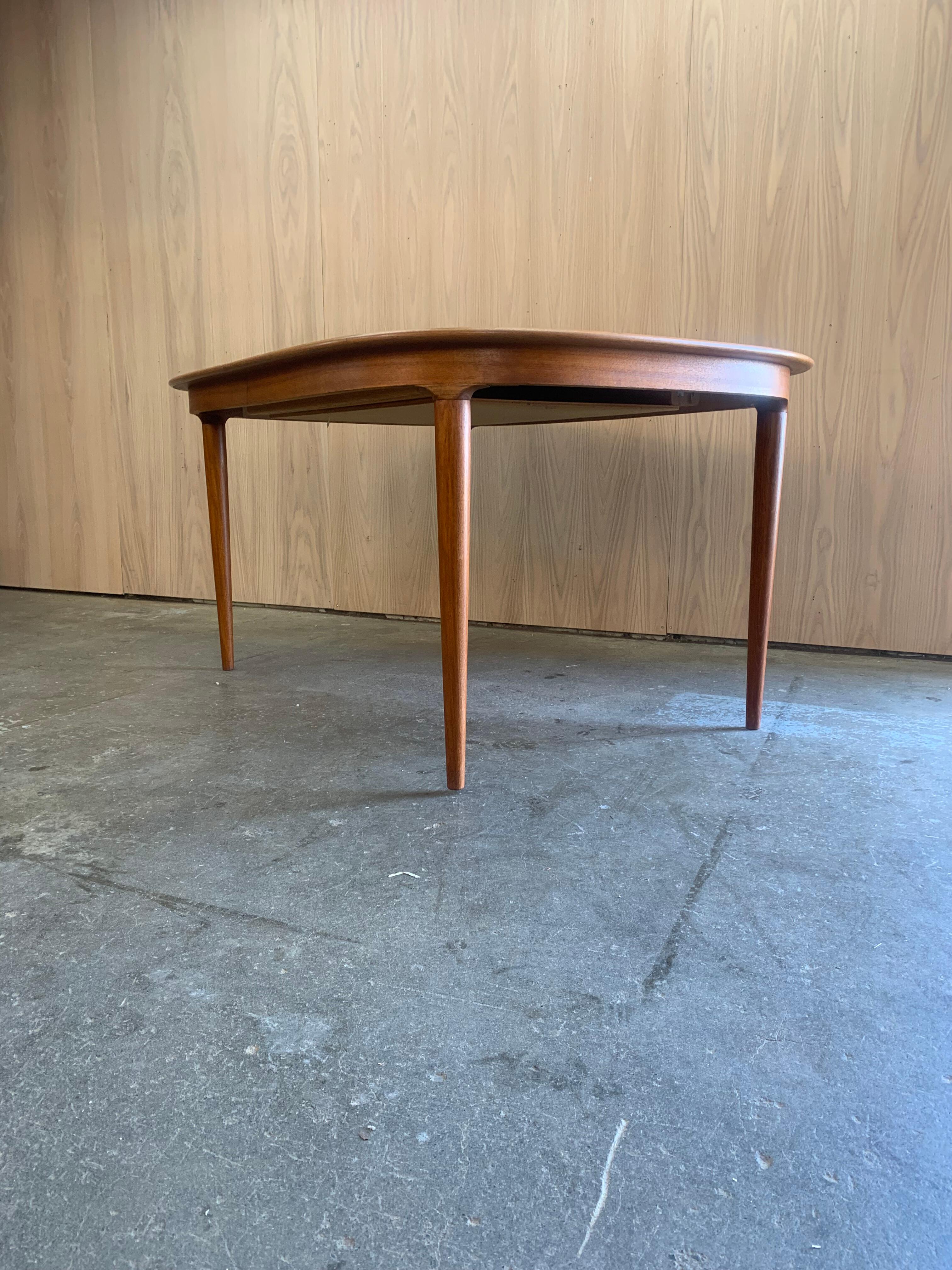 An exquisite example of Danish craftsmanship, this 1960s teak dining table by Skovmand & Andersen combines elegance, ingenuity, and sculptural detail. The subtly bowed top and softly rounded corners create a unique silhouette, while the tapered legs