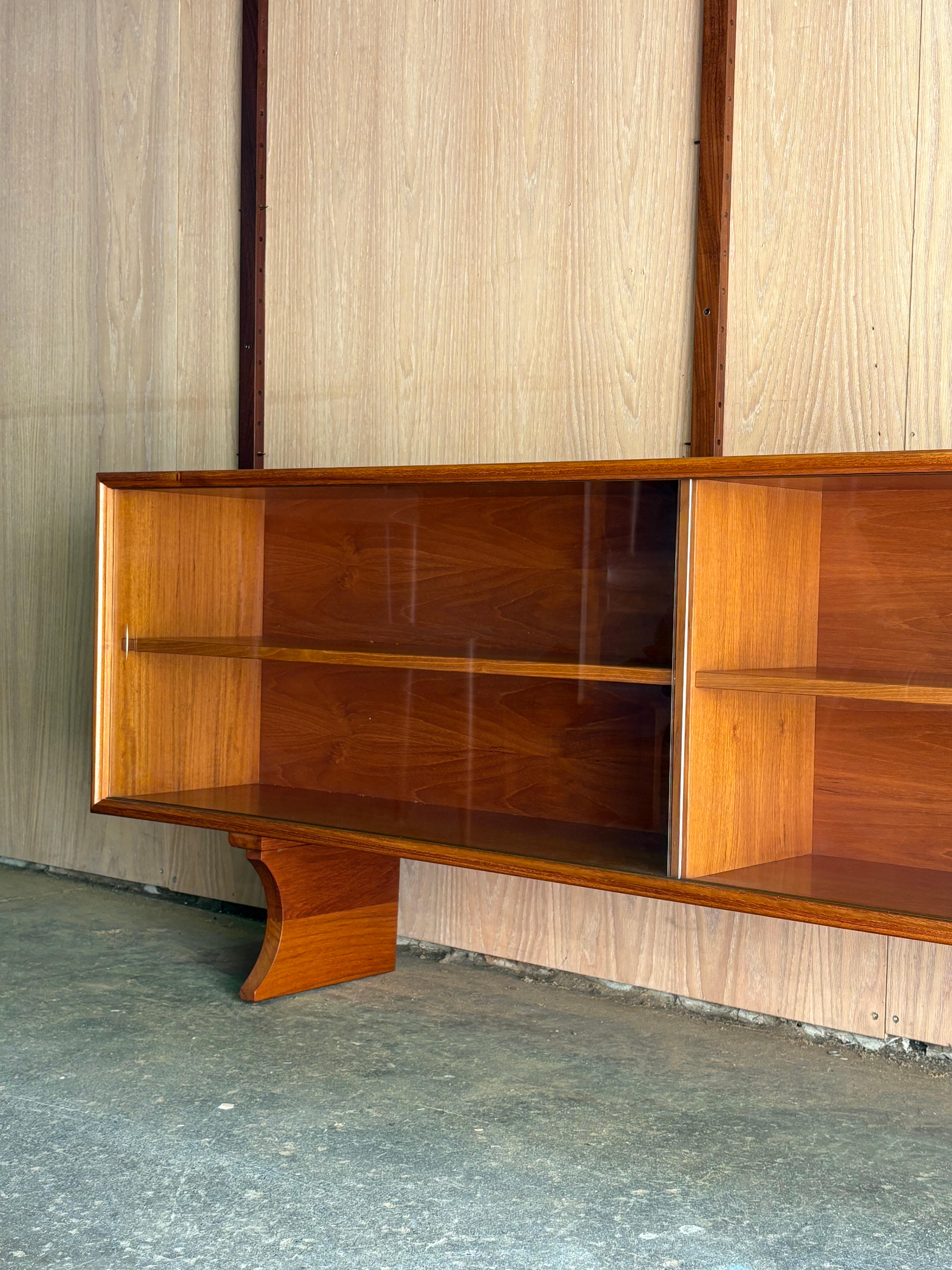 Eine vielseitige moderne dänische Teakholzvitrine aus den 1960er Jahren, hergestellt von ACO Møbler. Mit seinen klaren Linien, den Glasschiebetüren und dem elegant geschwungenen Sockel verkörpert dieses Möbelstück die raffinierte Schlichtheit und
