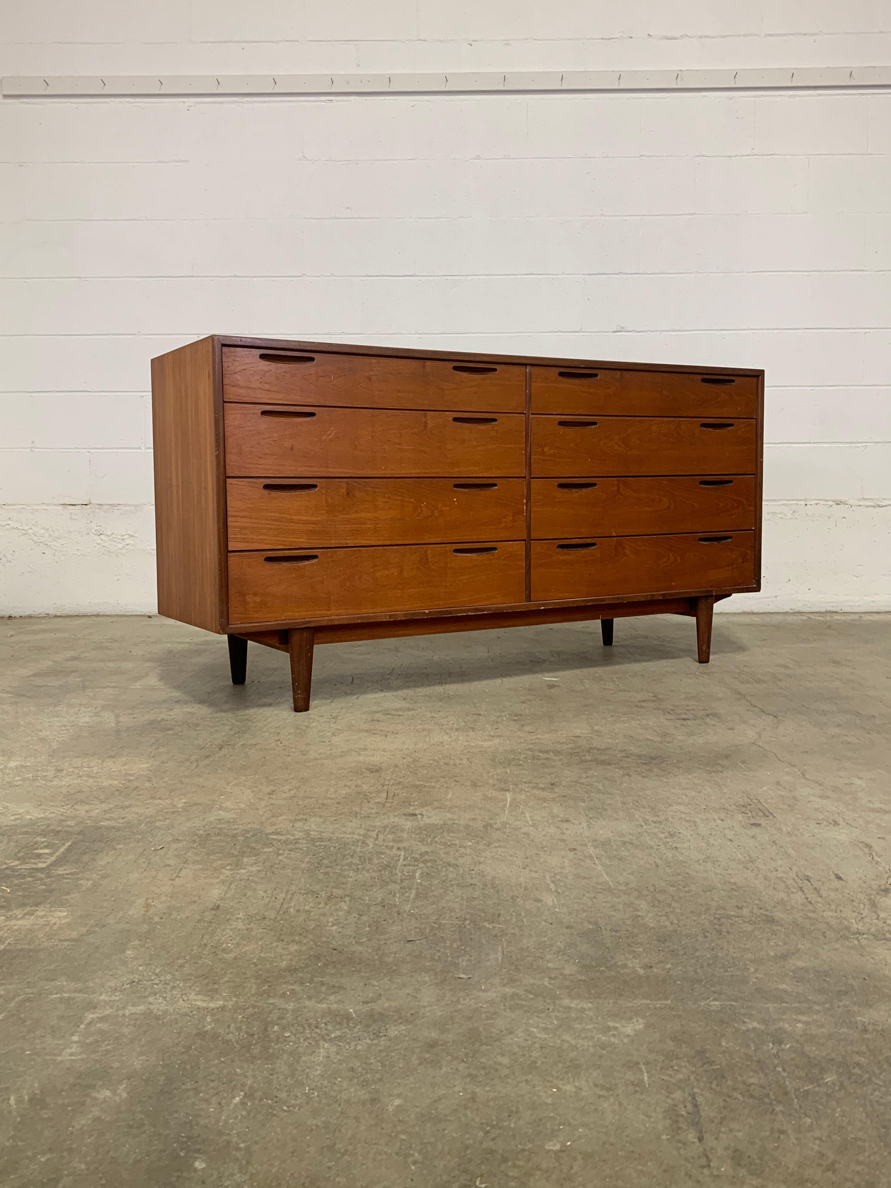 Designed in the 1950s by renowned Danish designer Ib Kofod-Larsen for Brande Møbelfabrik, this exceptional teak dresser is a standout example of Scandinavian design at its finest. Built from richly grained old-growth teak, it features sculpted inset
