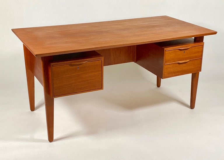 1960s floating top Danish teak desk with drawers on each side one side has two drawers and the other one large drawer. Figurative cathedral grained and book matched desk top. The back has storage cubes for books, objects, etc., so this can be placed