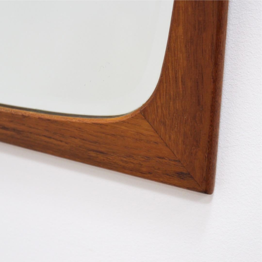 This mid-century wall mounted mirror was made in Denmark for Clark Eaton during the 1960s. Produced in teak, the frame a has a beautiful design and would be perfect for an entryway, living room or bedroom.