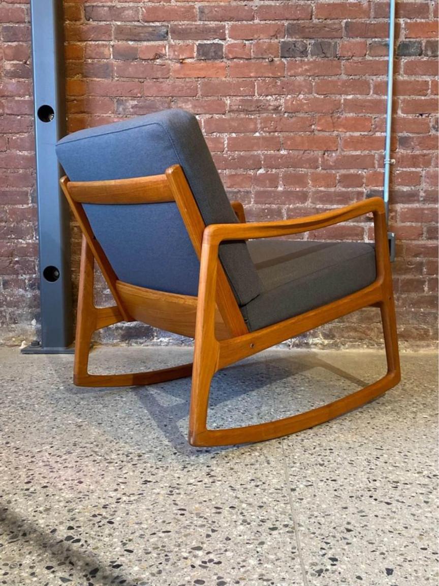 This 1960s Danish teak rocking chair, a breathtaking embodiment of mid-century Danish modernism, was intricately designed by Ole Wancher for France & Son. With subtly sculpted armrests, original sprung cushions, and a compact footprint, it exudes