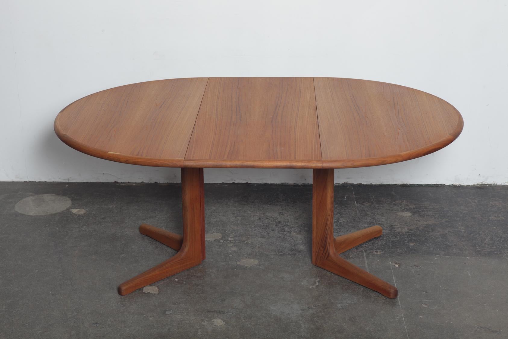 Danish 1960s round teak pedestal dining table with one centre extension. Newly refinished in a natural matte teak oil finish. Fully extended with the centre leaf, in an oval shape, it is 68