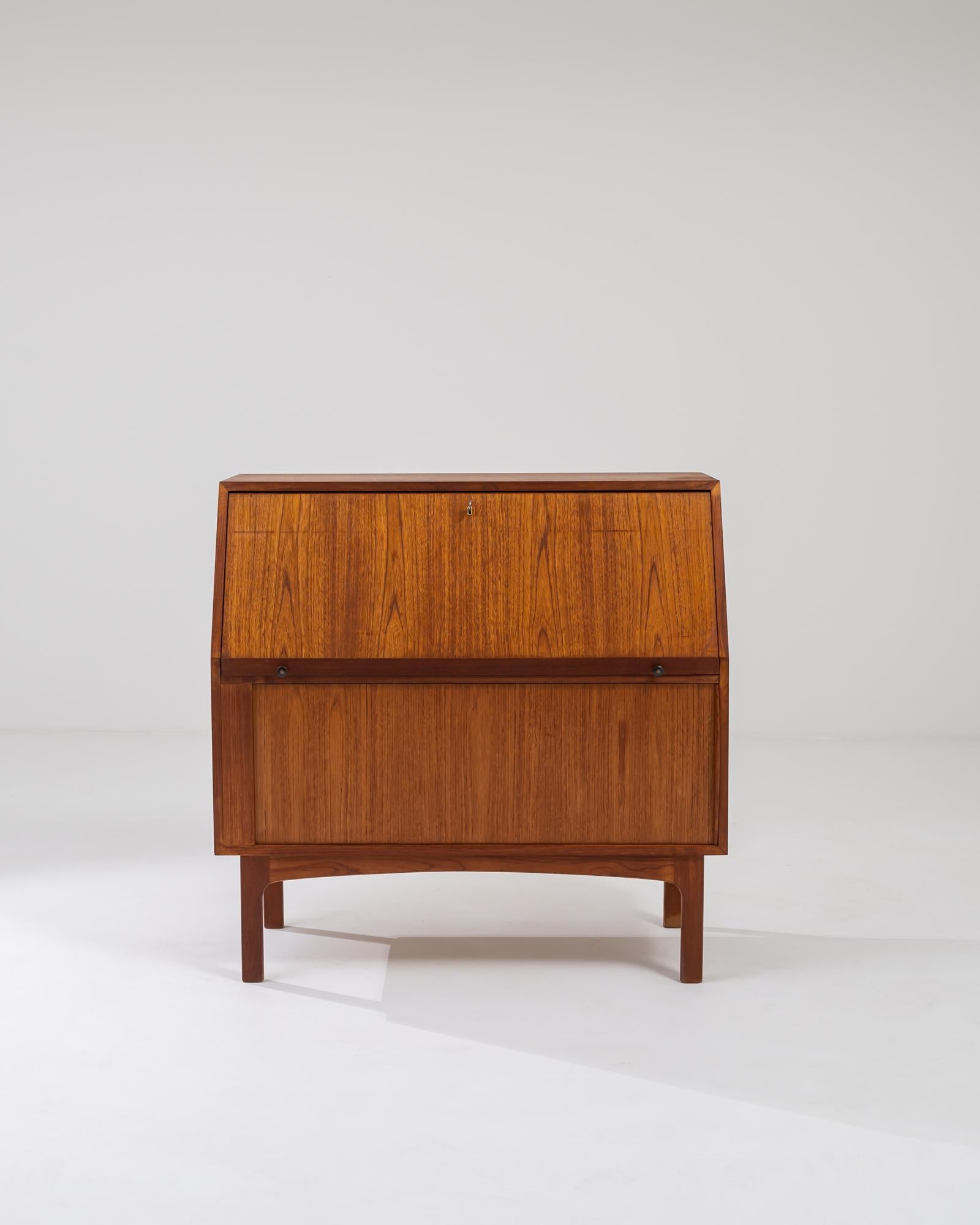 A wooden writing desk made in 1960s Denmark. Geometrically crafted from teak, this sharp writing desk ticks all the boxes of mid-century Danish design excellence. Its front face swings down to reveal a writing surface, several compartments, and four