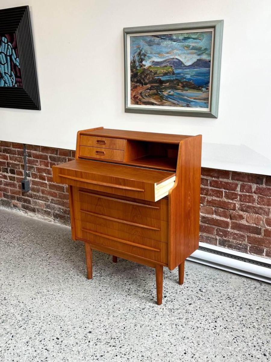 Step into mid-century sophistication with this charming 1960s teak secretary desk/vanity. Crafted with a rich teak wood grain, this piece exudes timeless elegance. Its versatile design features a pull-out vanity adorned with the original robin's egg