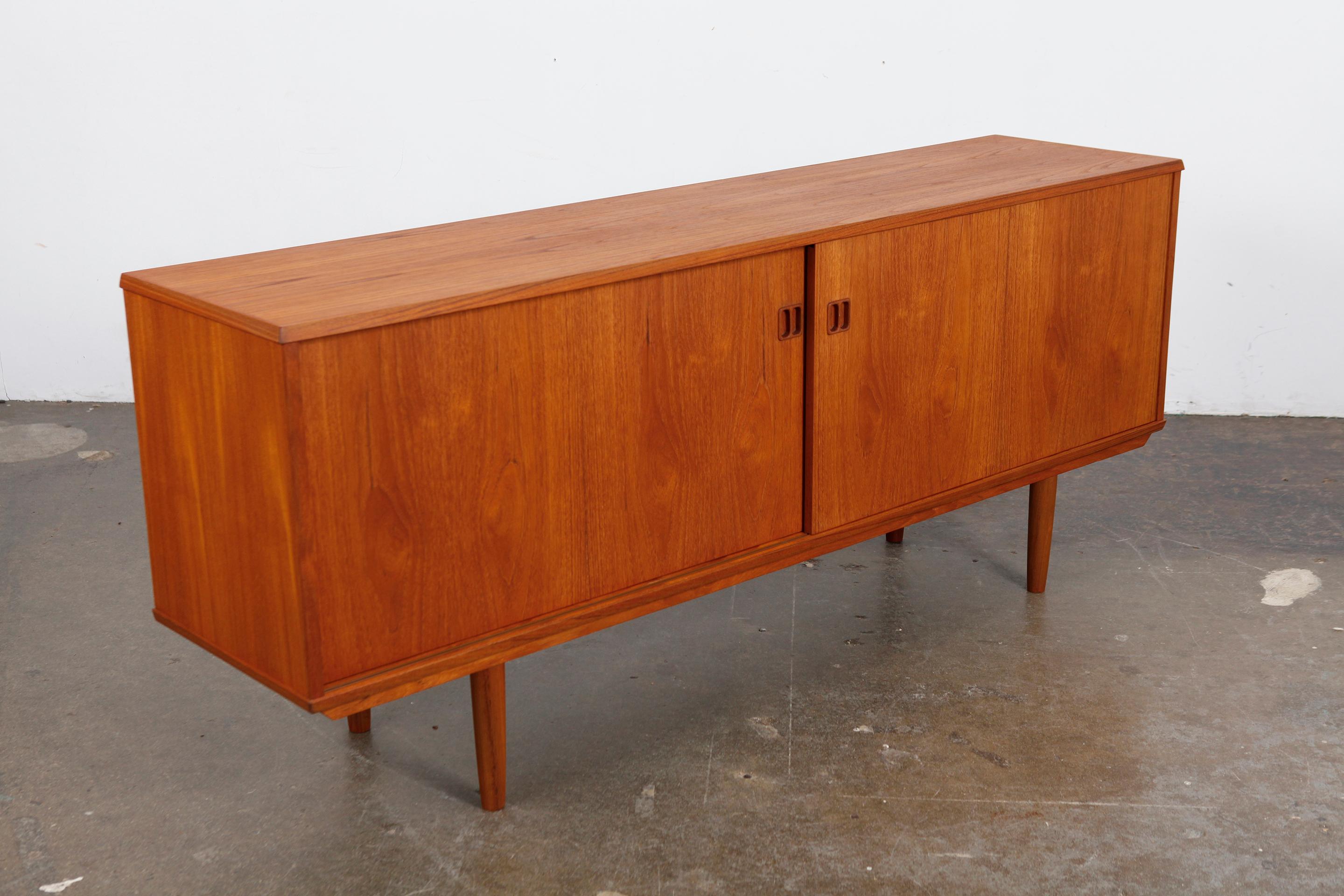 Danish Mid-Century Modern teak two door teak sideboard with Classic split square handles, sliding doors and tapering teak legs. Newly refinished in a natural teak oil finish, Denmark, 1960s.
