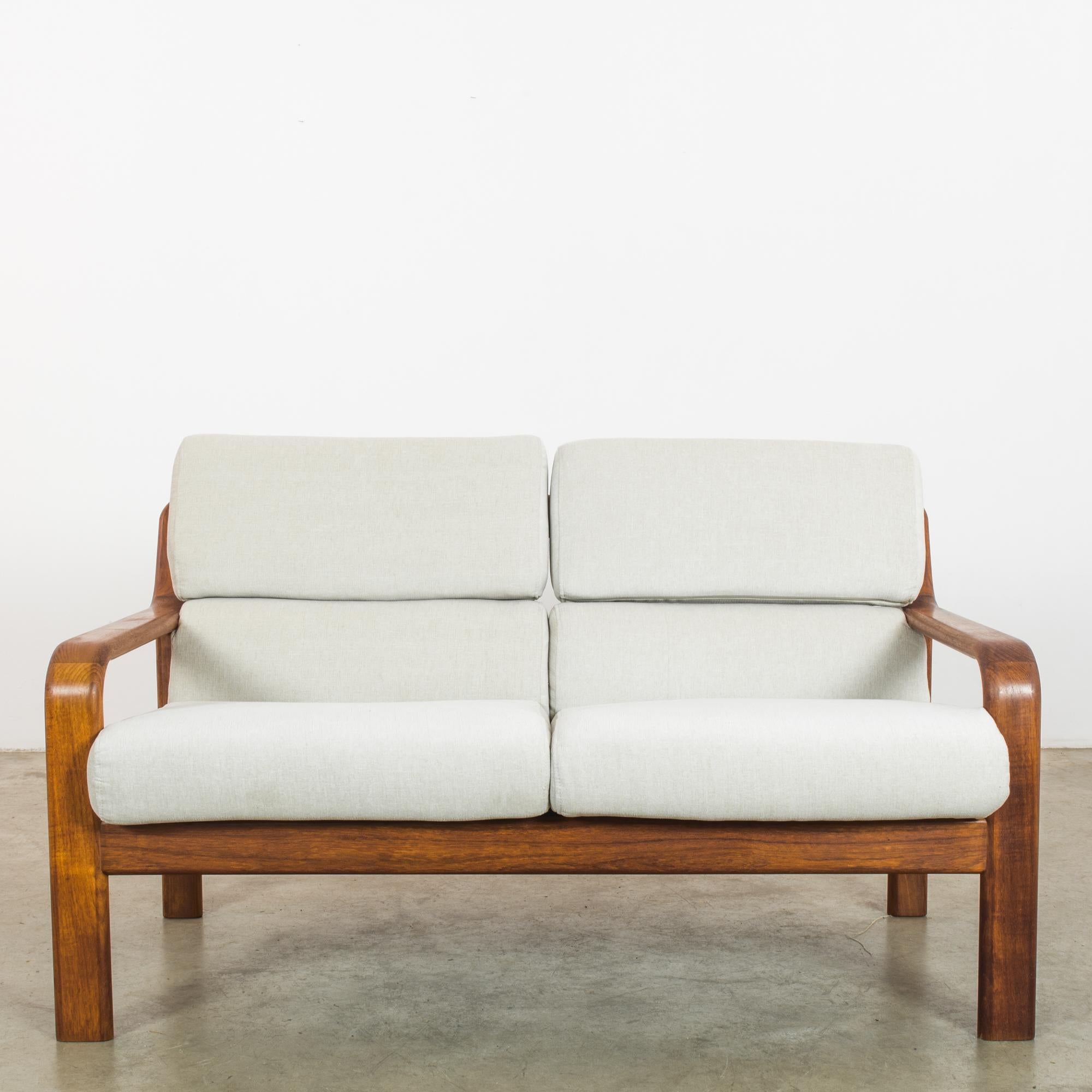 Discover mid-century charm with this 1960s Danish teak sofa, designed to elevate your living space with its timeless elegance. Crafted from rich, honey-toned teak wood, the frame showcases a fine grain that speaks to its high-quality heritage. The